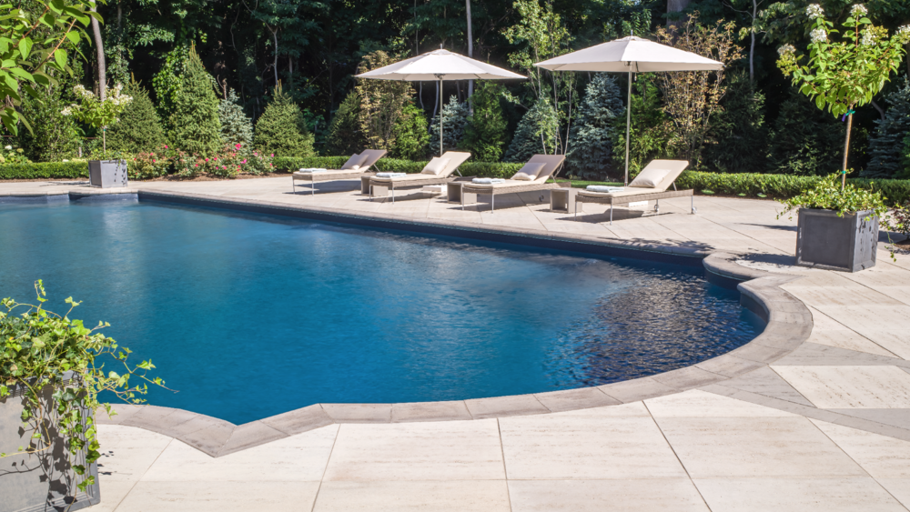 A swimming pool with lounge chairs, white umbrellas, and lush greenery in the background.