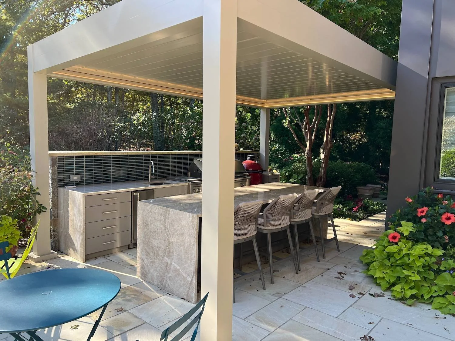 Luxury outdoor kitchen and dining area beneath a custom white pergola by Gary Duff Designs
