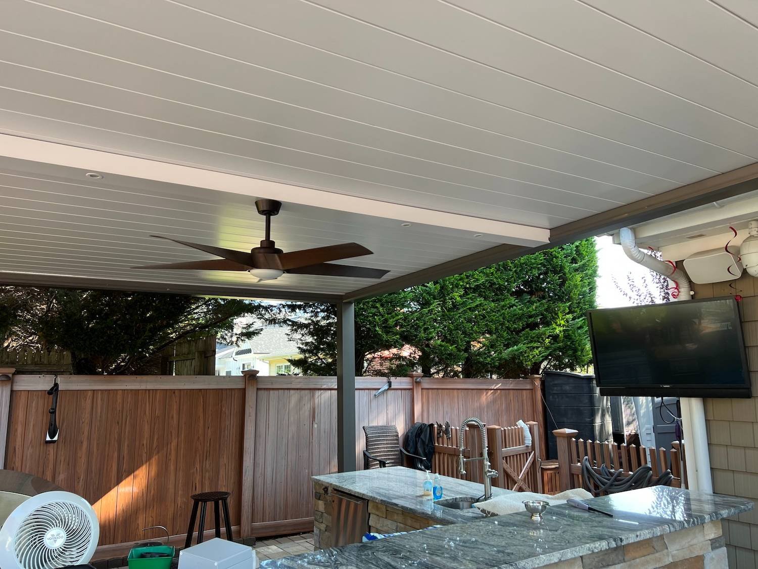 Modern pergola with adjustable louvered roof and ceiling fan installed by Gary Duff Designs