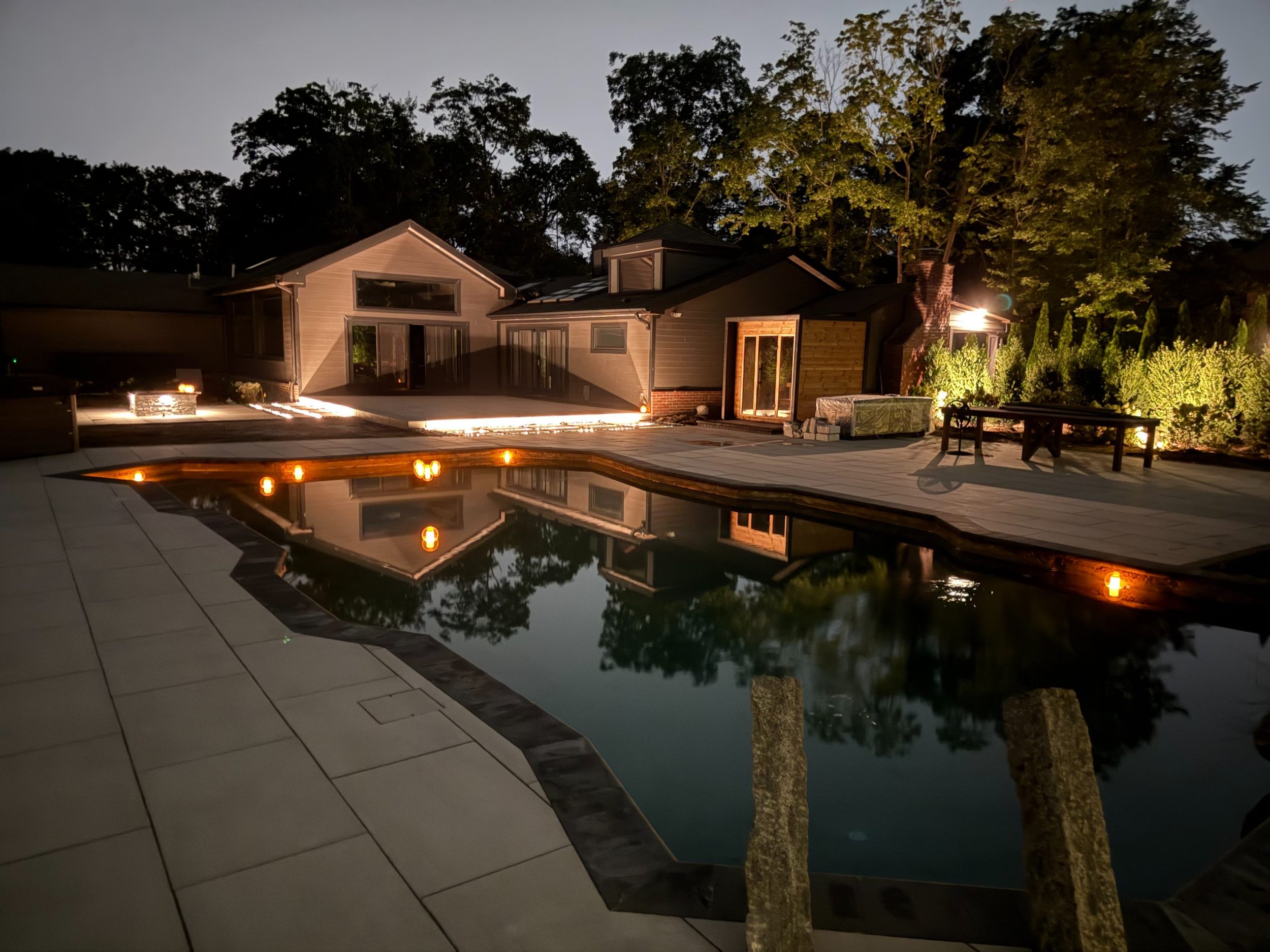 Soft landscape lighting framing trees and shrubs in Syosset, NY