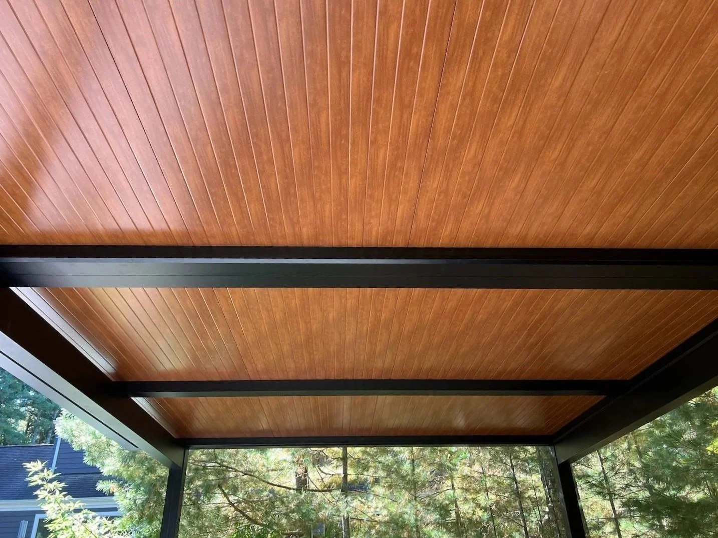 Woodgrain pergola ceiling installed by Gary Duff Designs with exposed beams and warm natural finish