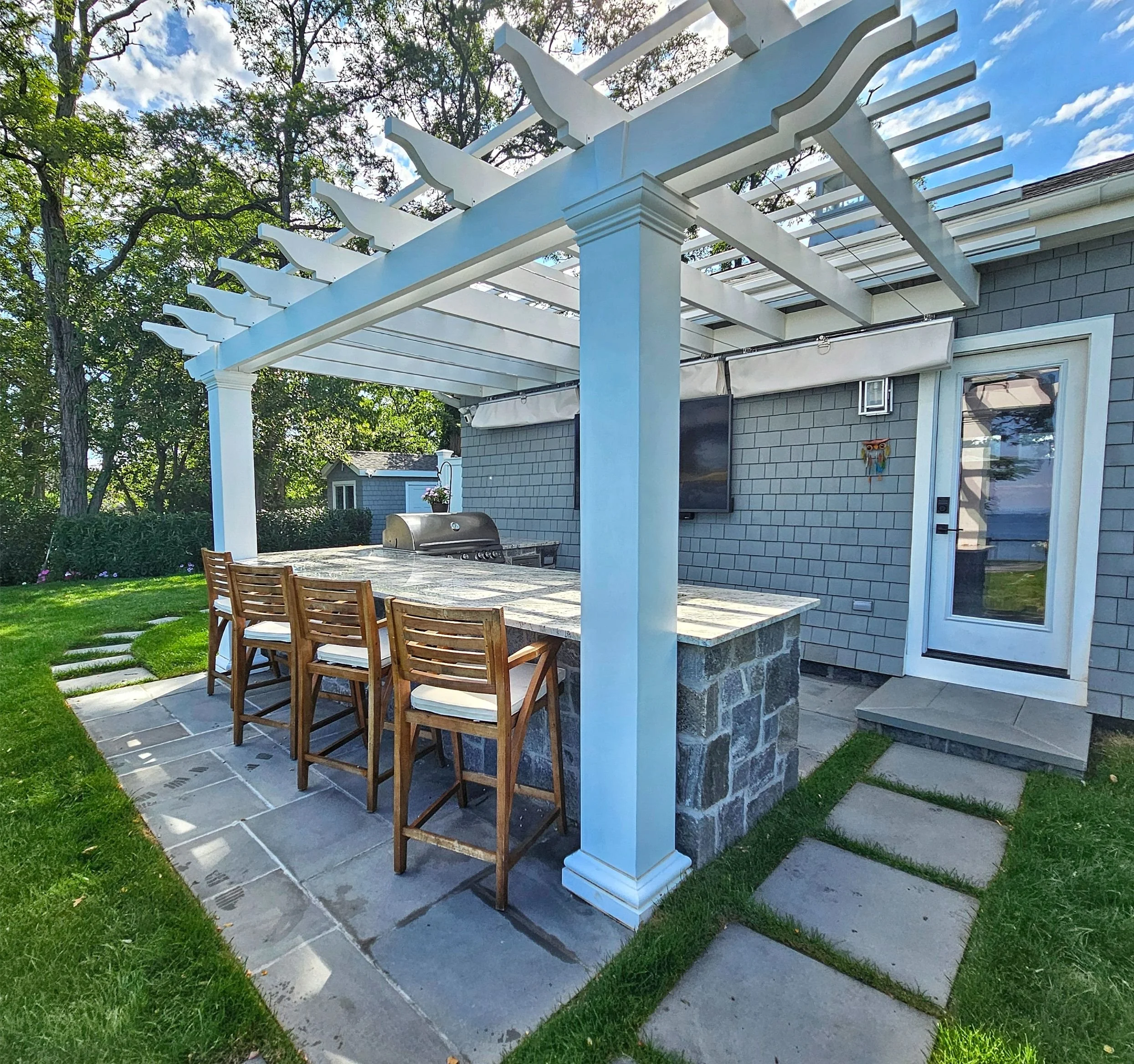 Outdoor kitchen BBQ station with integrated grill, storage, and stone surround in Mt. Sinai, NY