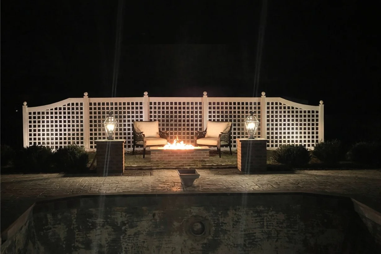 A gas fire pit surrounded by Adirondack chairs and stone pavers in Northport, NY