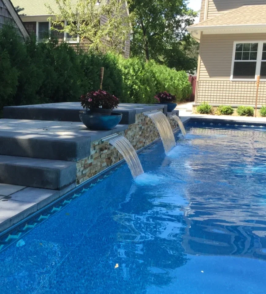 Pool water wall with sheer descents integrated into a custom swimming pool in Old Westbury, NY