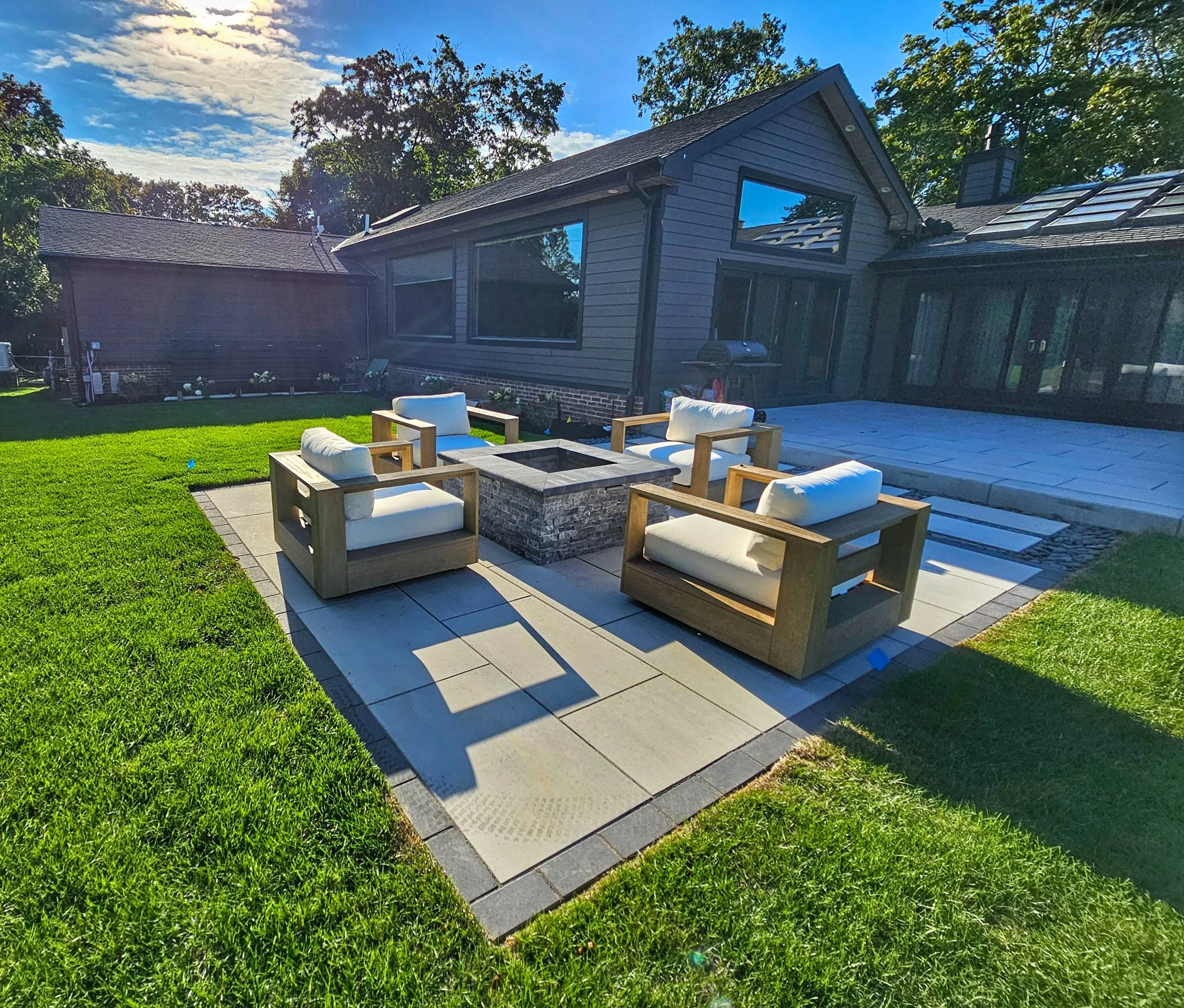 A modern backyard fire pit with concrete fire bowl and lounge seating in Sag Harbor, NY