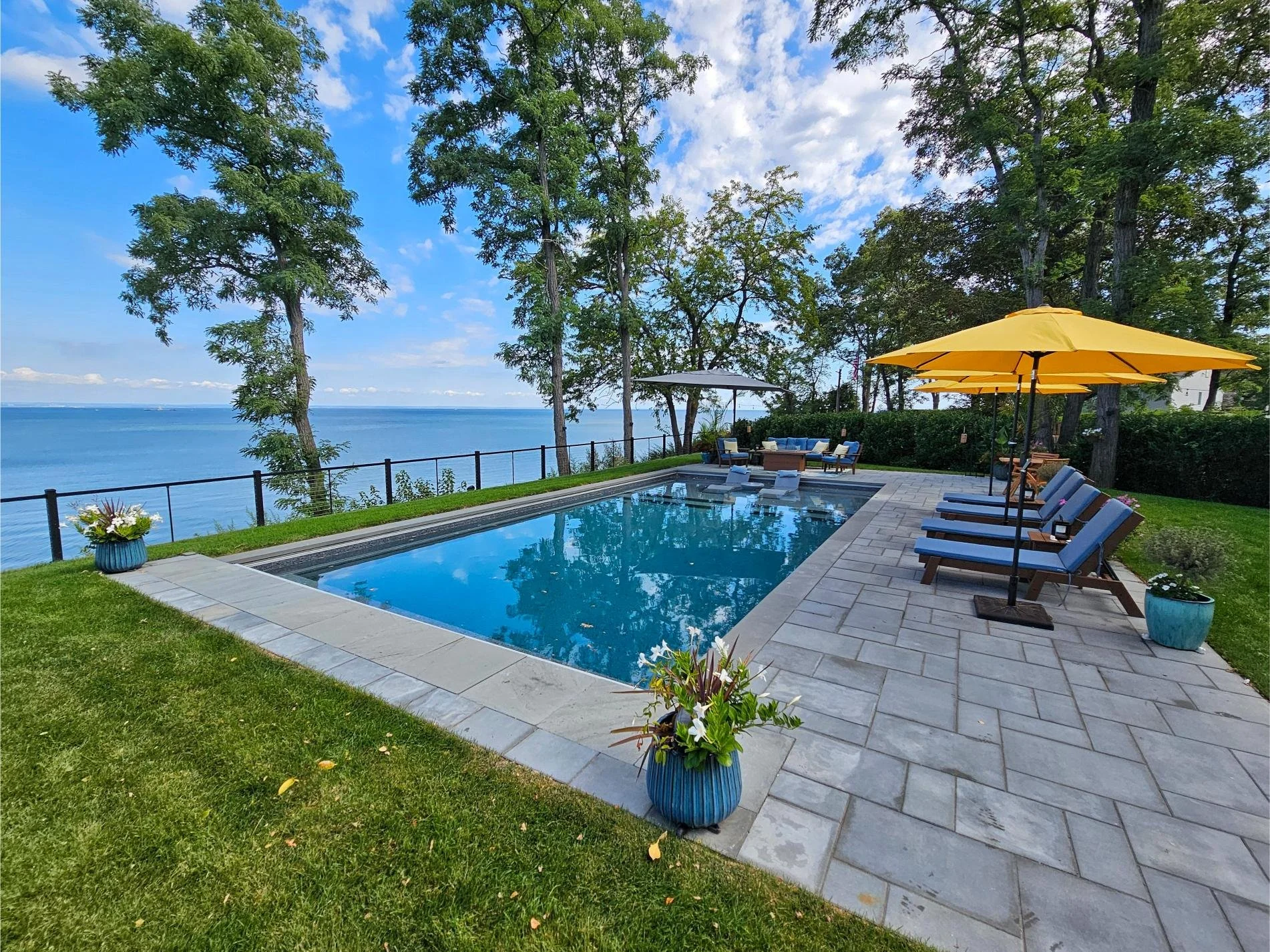 Pool patio design with clean pavers and space for loungers beside a custom swimming pool in Huntington, NY