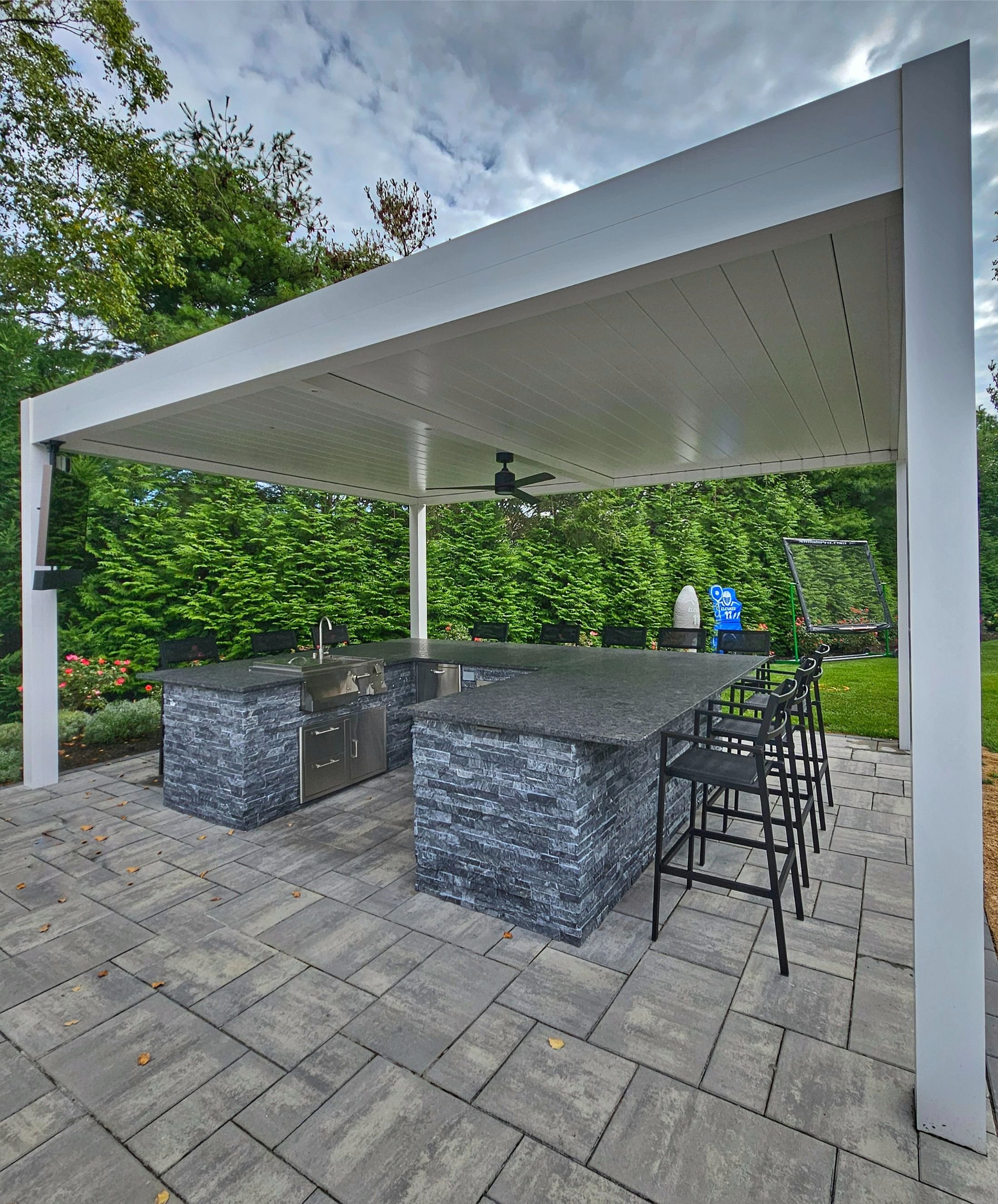 Outdoor kitchen with a built-in outdoor bar, stone counters, and seating for entertaining in Manhasset, NY