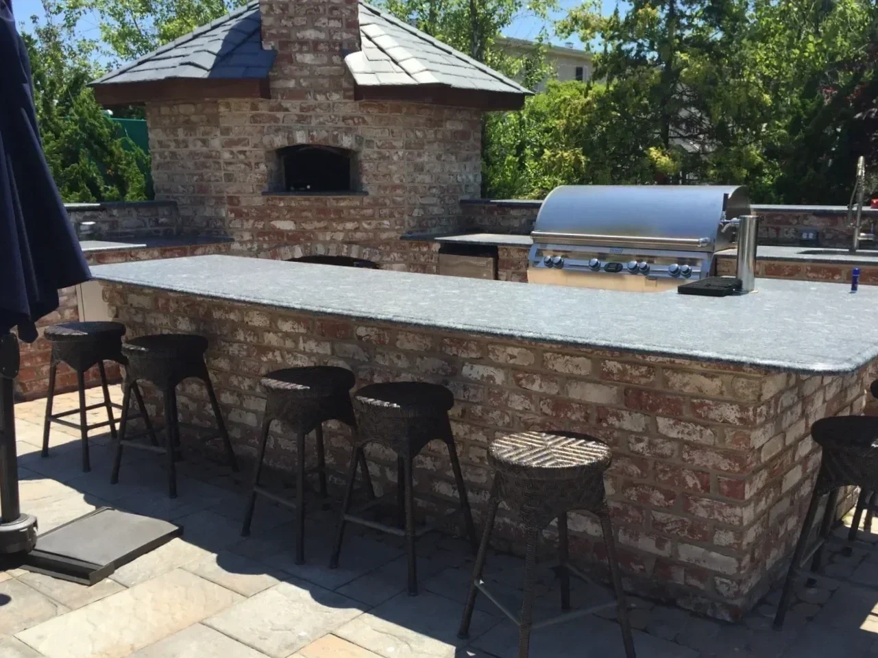 Outdoor kitchen featuring a custom brick pizza oven and stone prep surfaces in Sag Harbor, NY