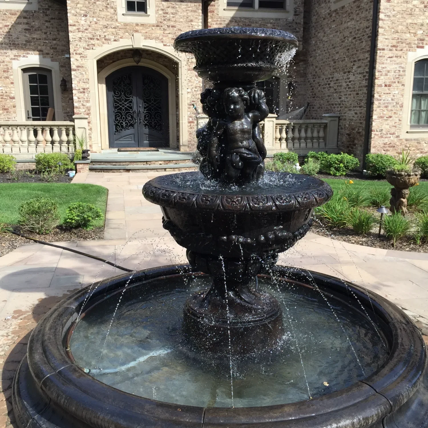 Classic courtyard fountain with carved stone basin near the home entrance in Manhasset, NY