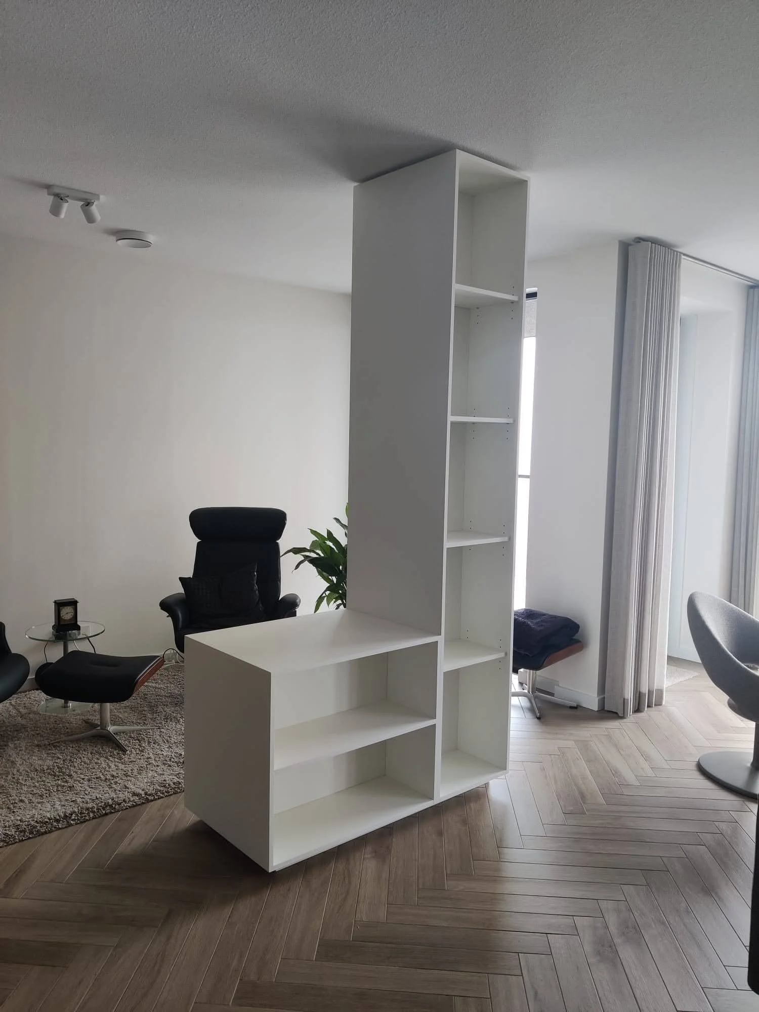Roomdivider op maat van Tije Interieur – plafondhoge witte kast met open vakken, modern design en strakke afwerking, geplaatst in woonkamer met visgraat vloer in Zutphen (Gelderland).