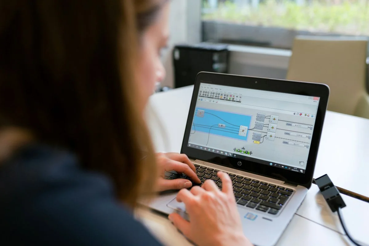 A person using a laptop with a flowchart or diagram on the screen, in a room with a large window in the background.