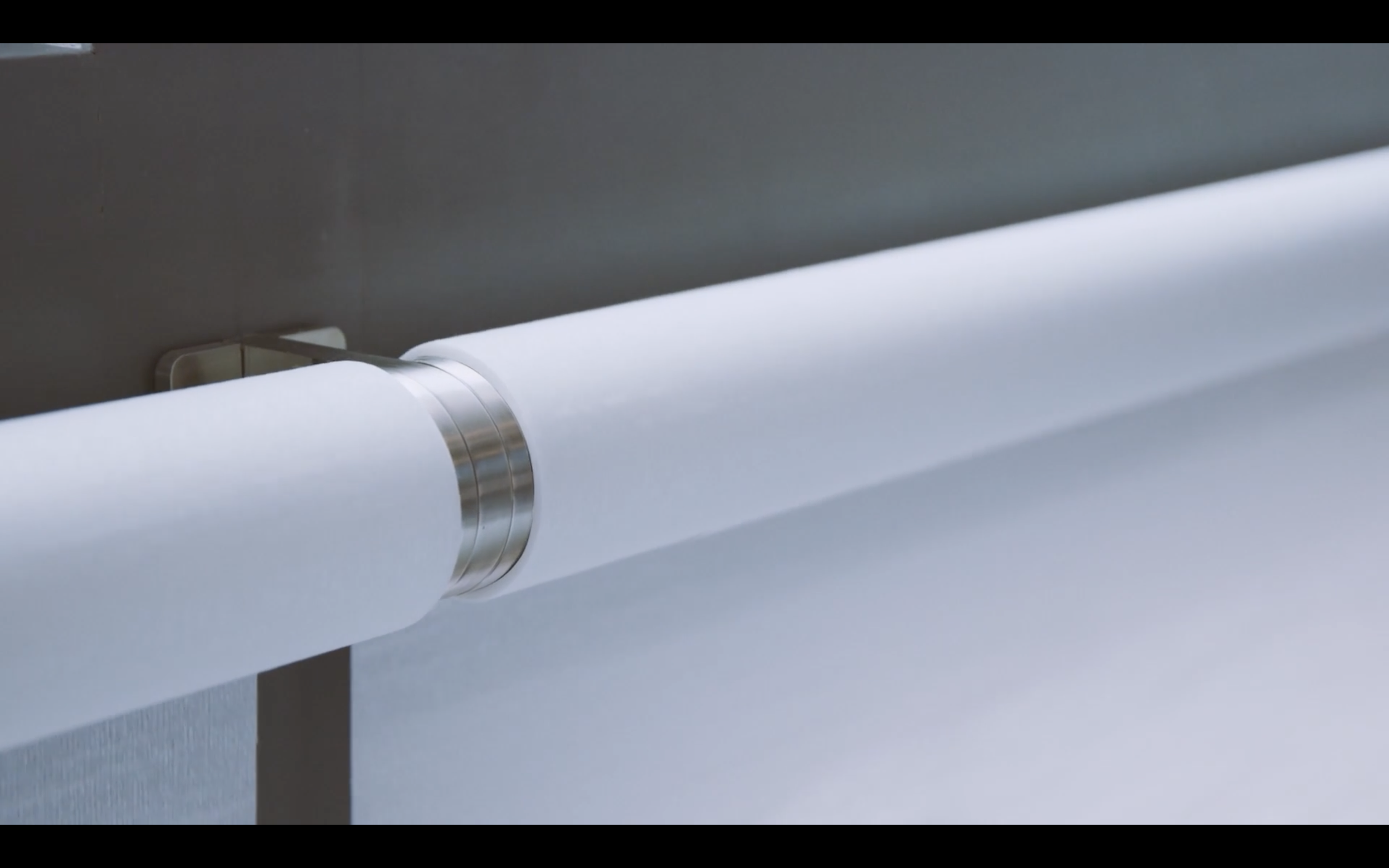 A white paper roll mounted on a metallic dispenser or holder, with part of the paper unrolled and extending downward.