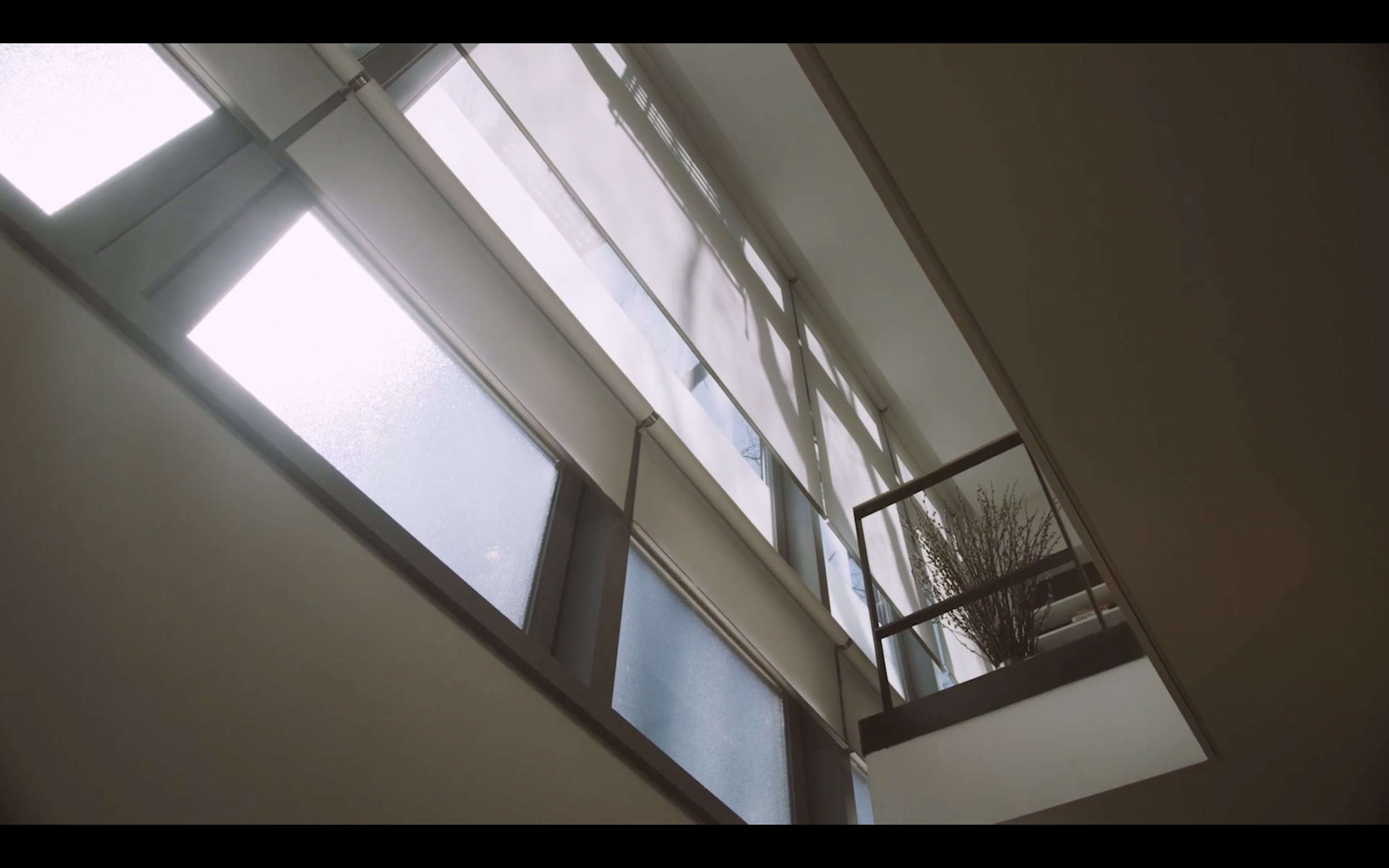 View of a parking lot and building through a window with blinds, taken from inside a room.