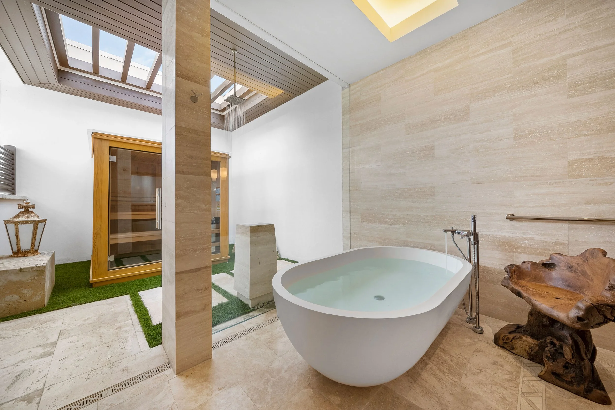 A modern bathroom with a freestanding bathtub, wooden sauna, and a skylight ceiling with natural light.