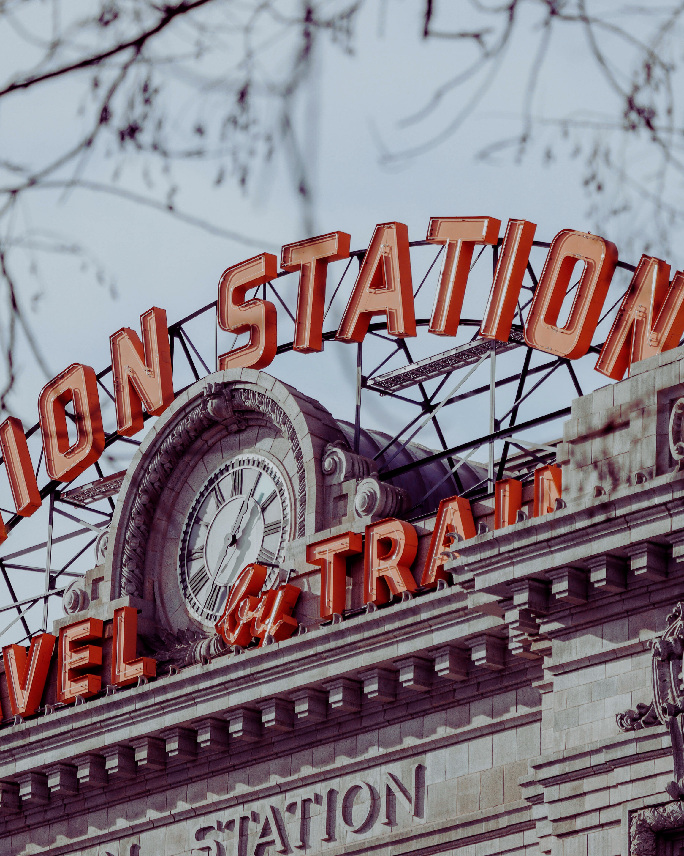 Close-up of a historic train station building with a large clock and neon sign reading 'Union Station'.