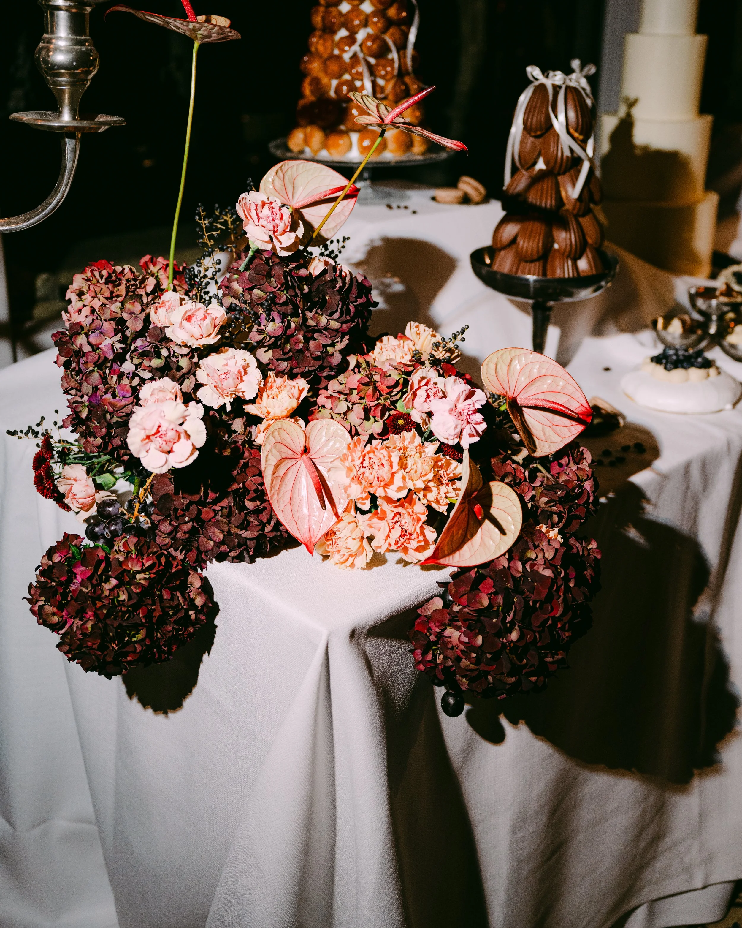 Décor de table avec des fleurs, chocolats et gourmandises lors d'un événement élégant.