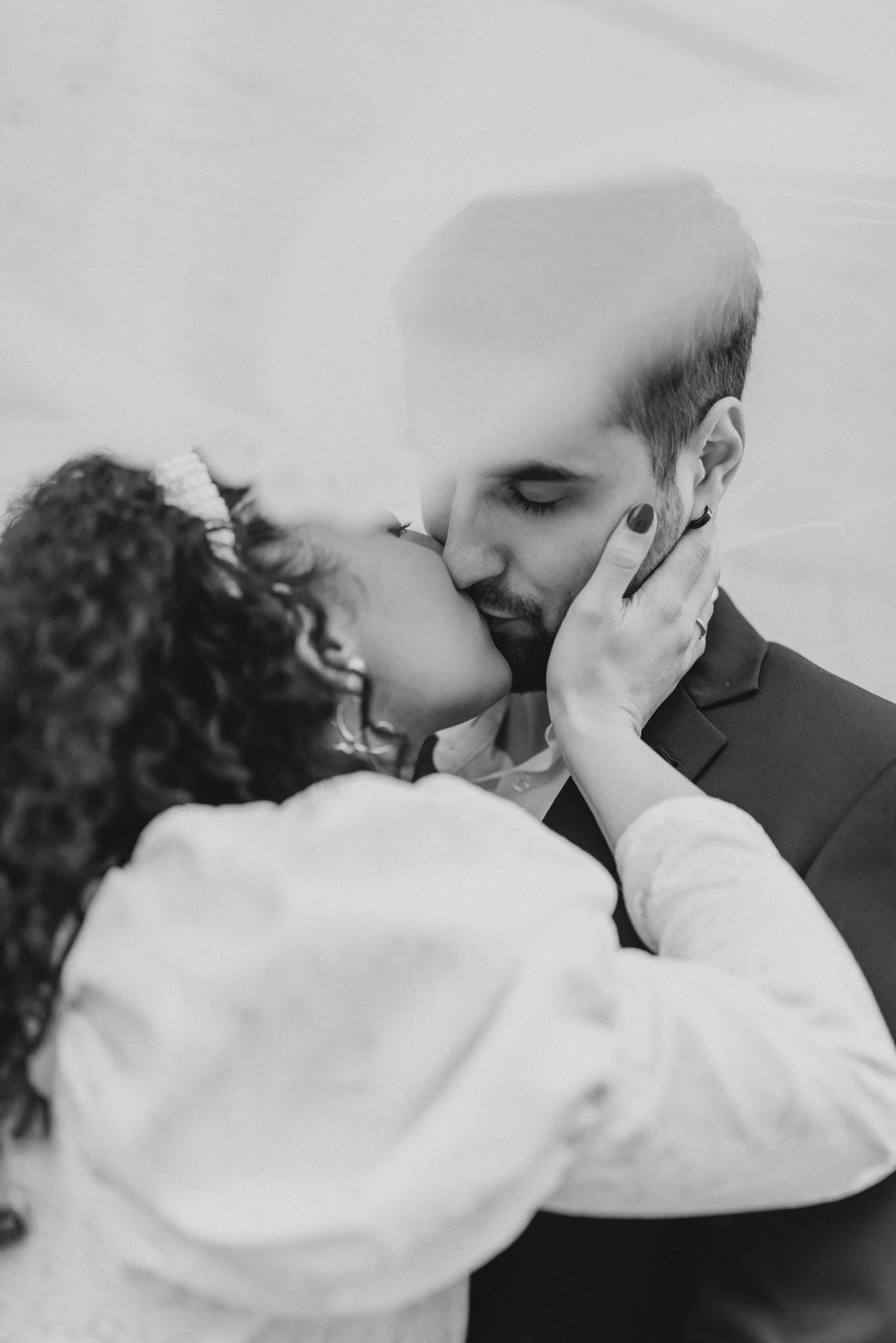 Un couple s'embrassant tendrement, la femme tenant le visage de l'homme dans ses mains.