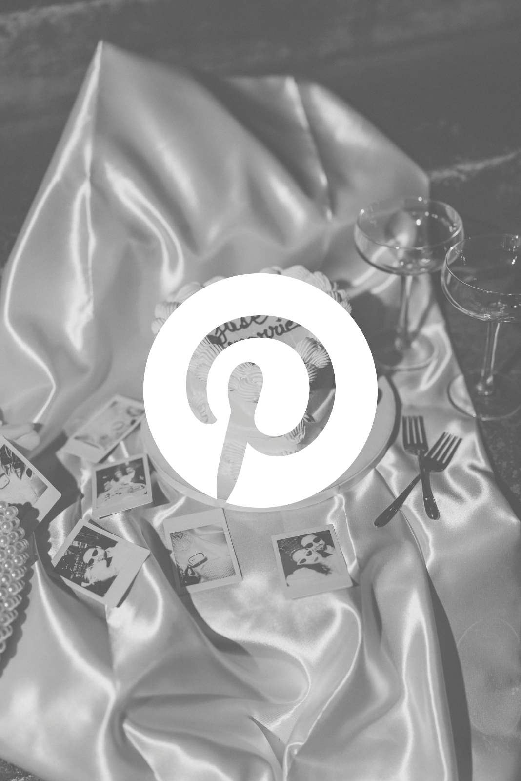 Table de fête avec un gâteau, deux verres à vin, fourchettes et photos en polaroid, décorée avec un tissu en satin.