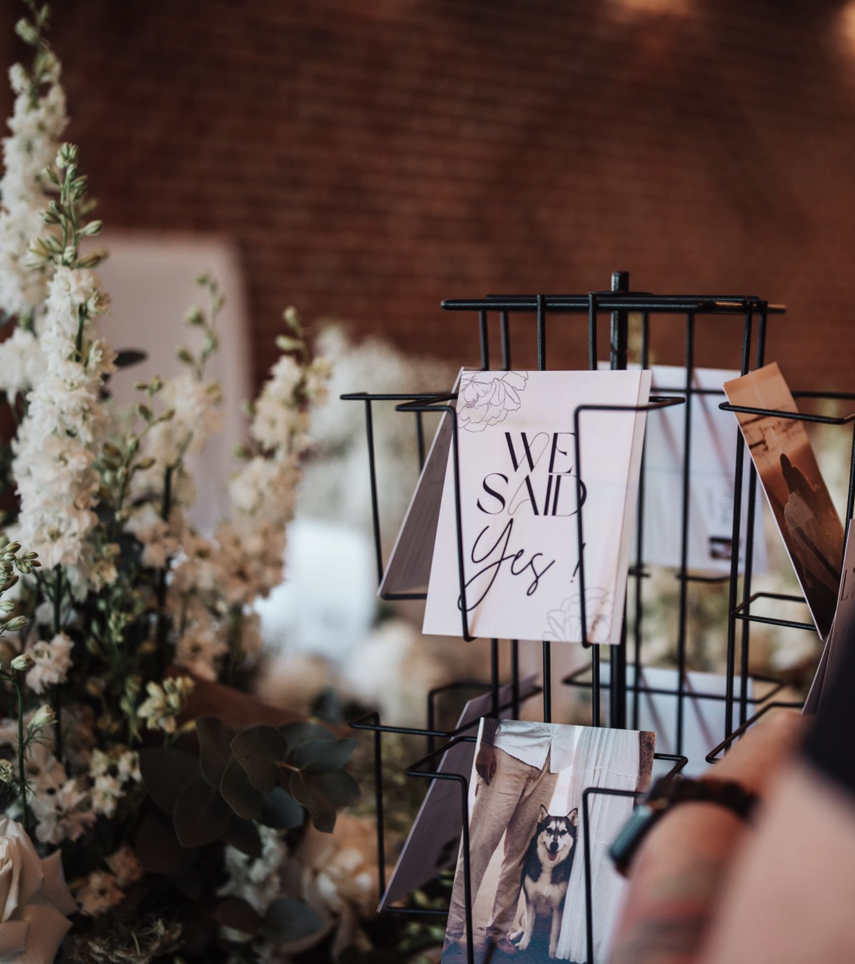 Une table avec des fleurs blanches et une affiche sur un porte-documents noir qui dit "We Said Yes!"