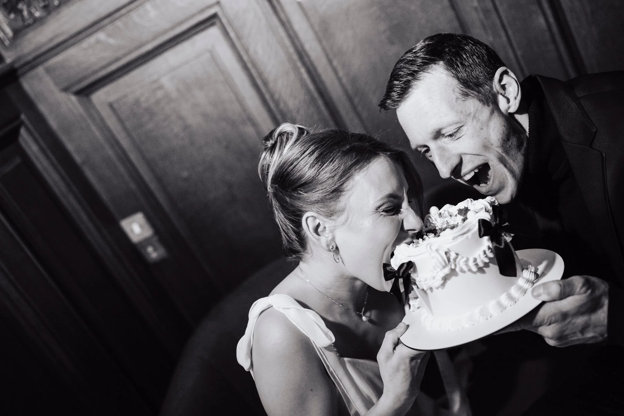Un couple habillé élégamment partageant un gâteau de mariage à une célébration.