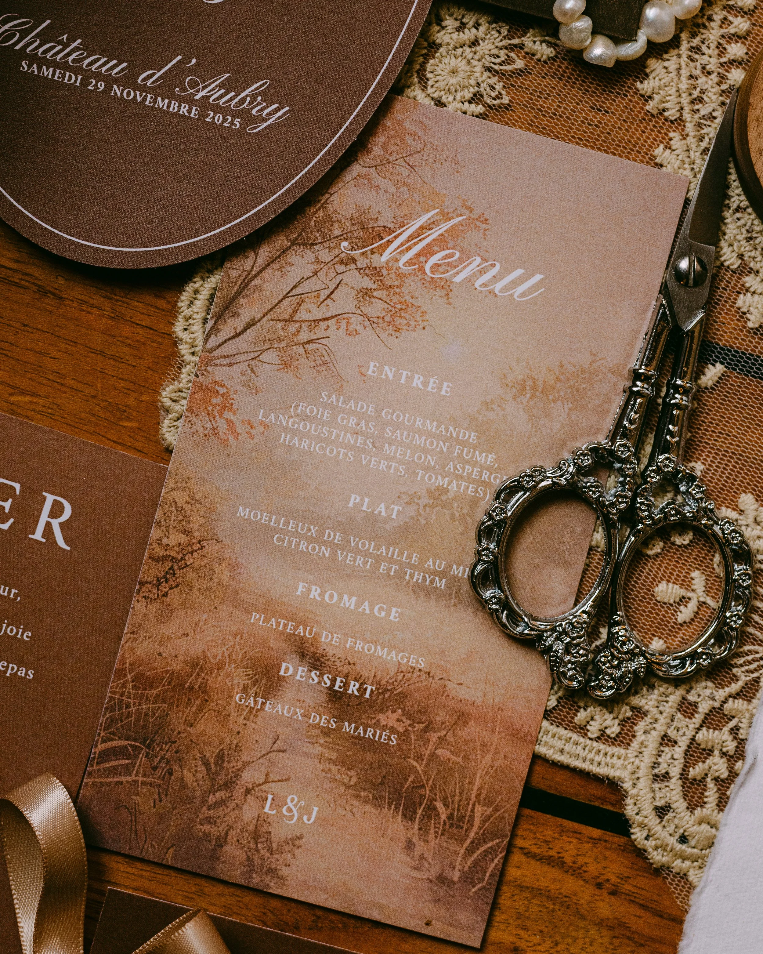 Carte de menu avec un décor automnal, comprenant une section d'entrée, plat, fromage, dessert, et une illustration d'arbre aux couleurs automnales. Scissors en ornements argentés posés à côté.