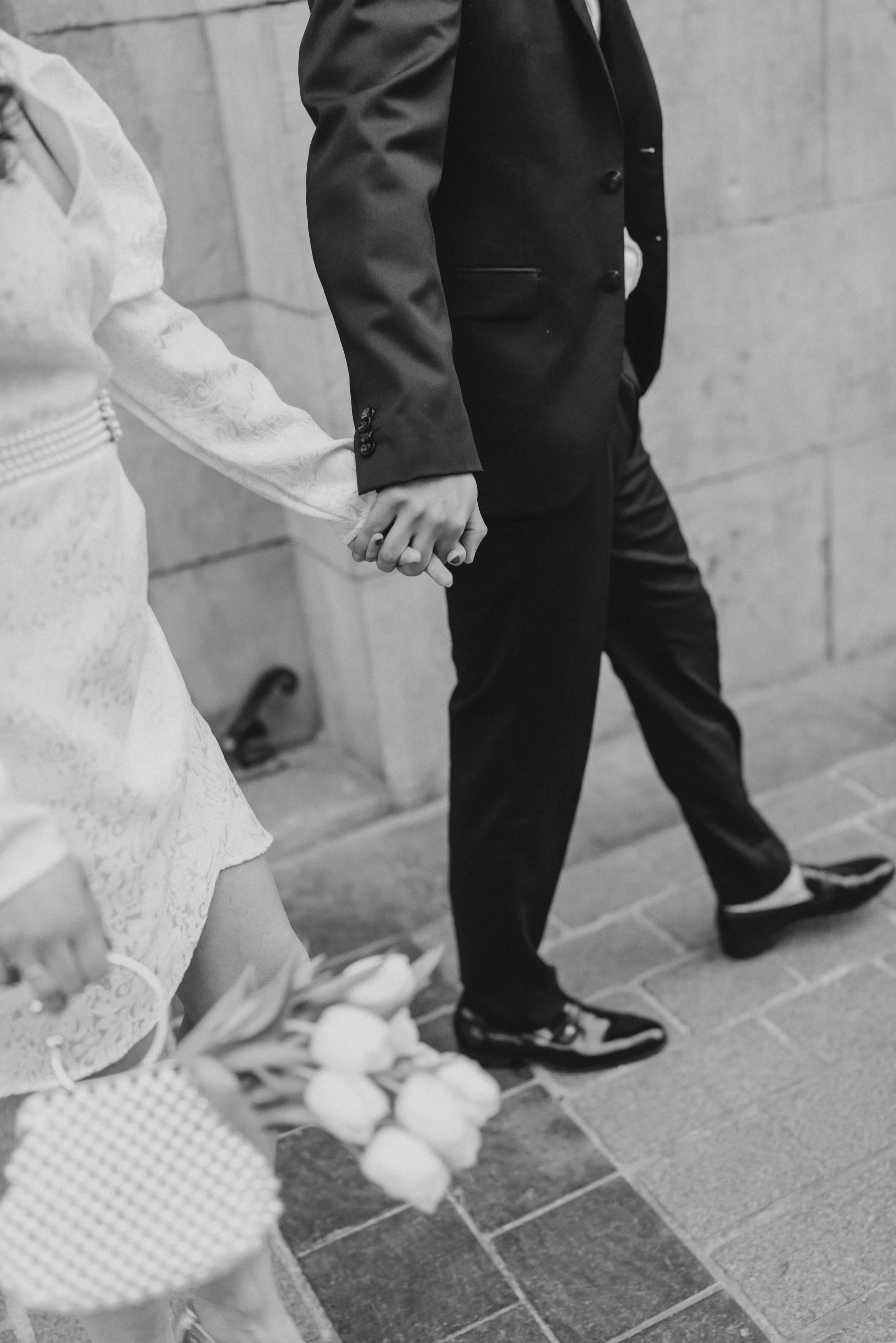 Un couple main dans la main, vu partiellement, marchant dans une journée nuageuse.