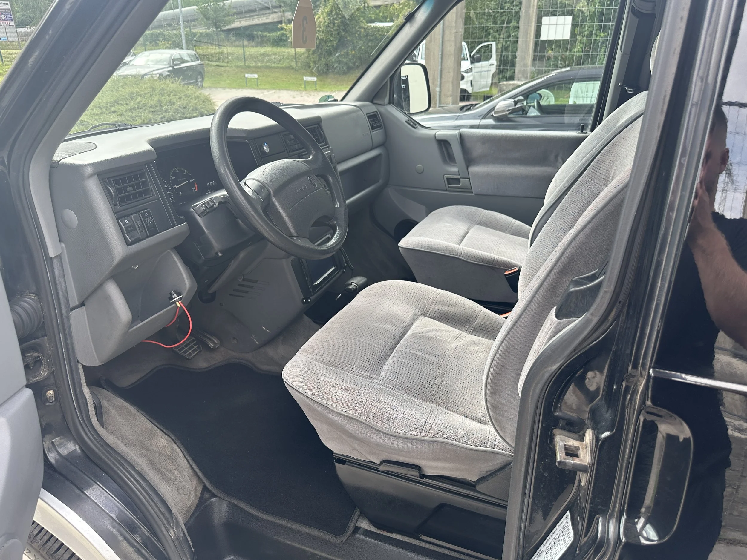 Innenansicht eines älteren Transportfahrzeugs mit grauem Sitz und Armaturen, in einer Fahrzeughalle geparkt.