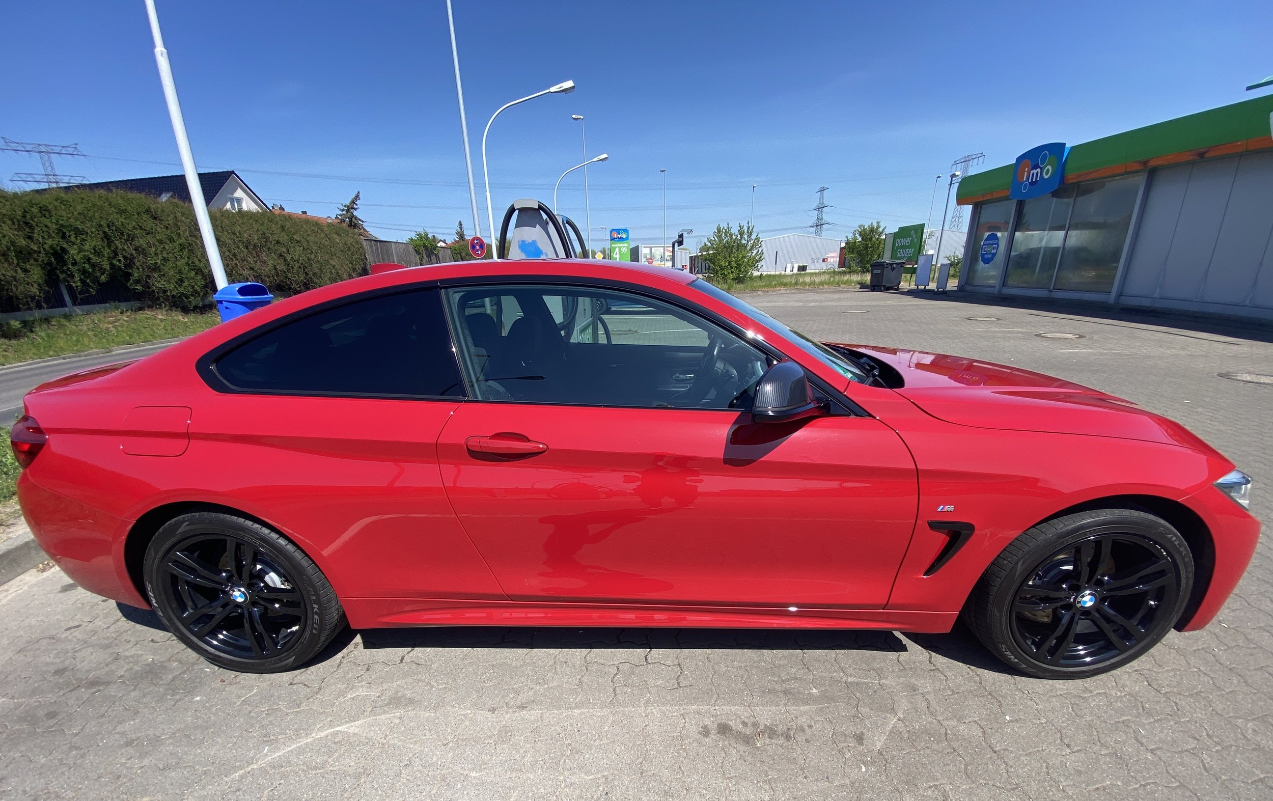 Roter BMW M Sport Coupé parkend in einer Tankstelle