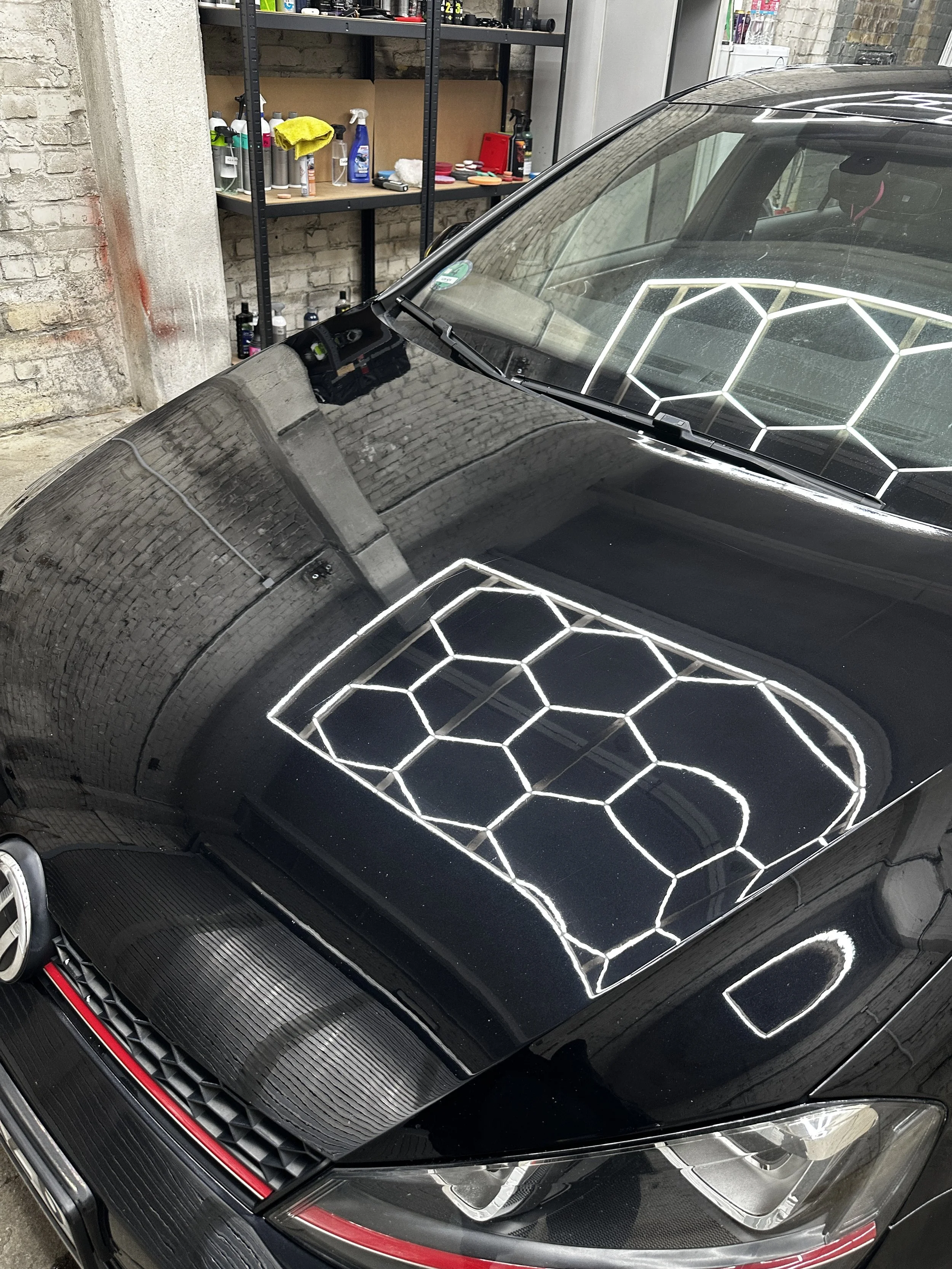 Nahaufnahme eines schwarzen Autos, das in einer Garage geparkt ist, mit einer speziellen weißen Gehäusezeichnung auf der Motorhaube.