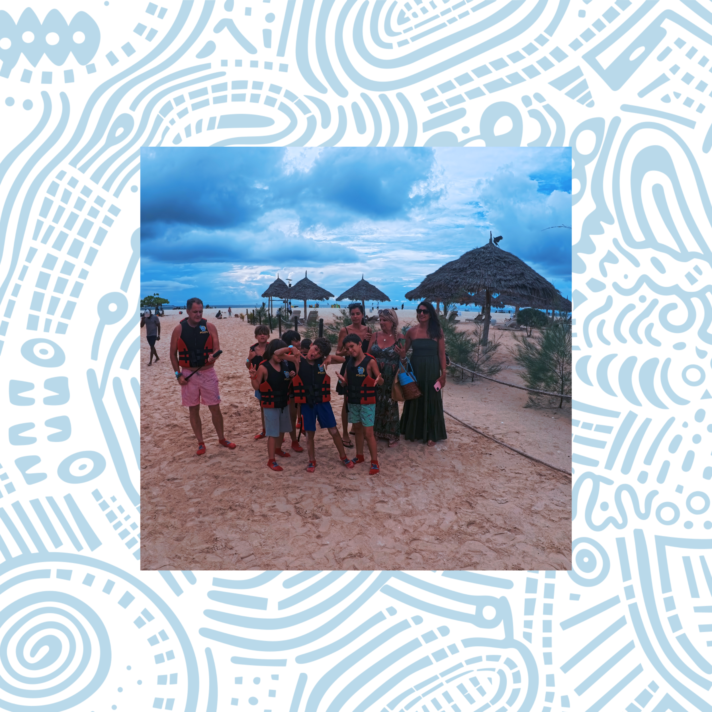 A group of children and adults on a beach wearing life jackets, with thatched umbrellas and cloudy sky in the background.