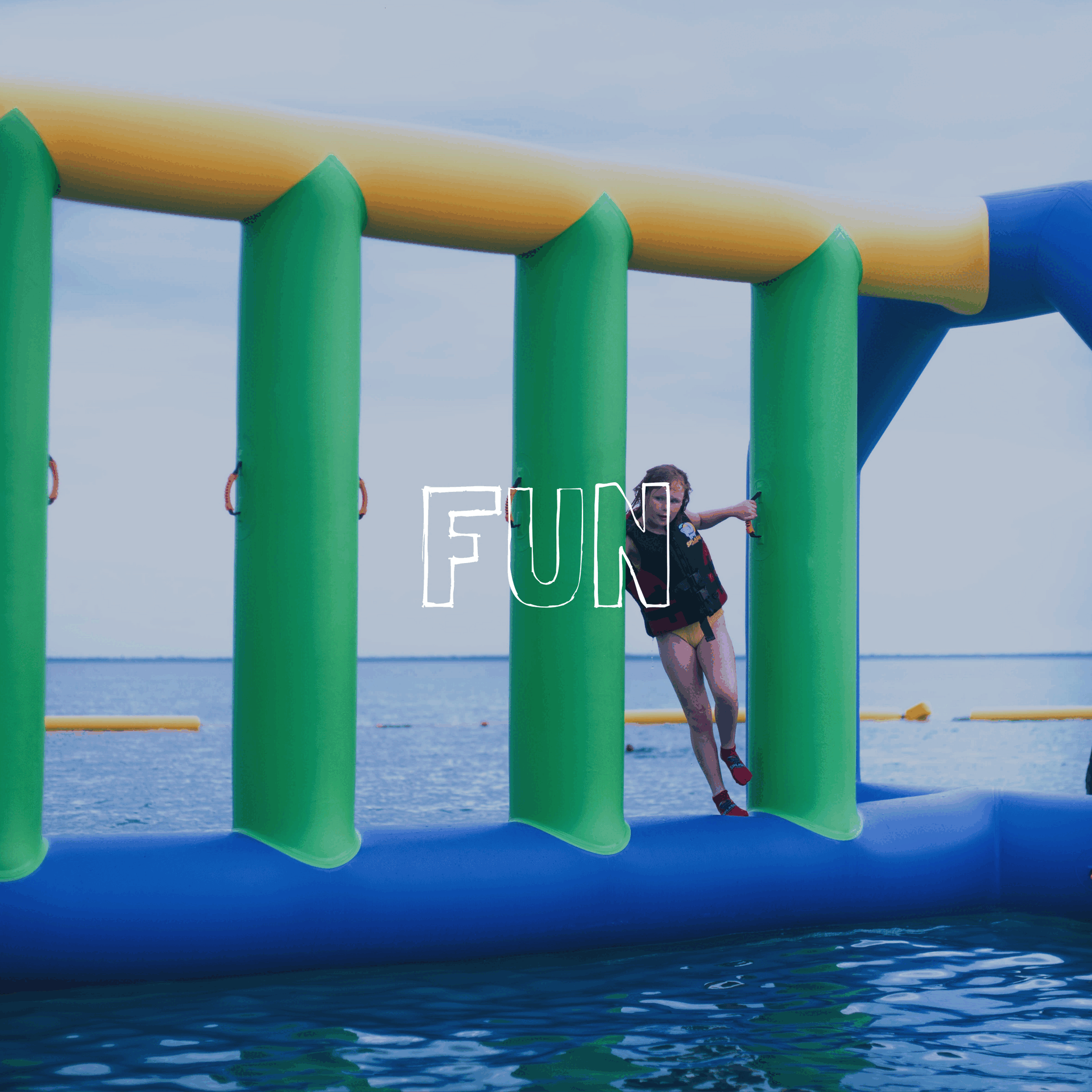 Child playing on an inflatable water obstacle course outdoors over a body of water with a cloudy sky, with the word 'FUN' overlayed.