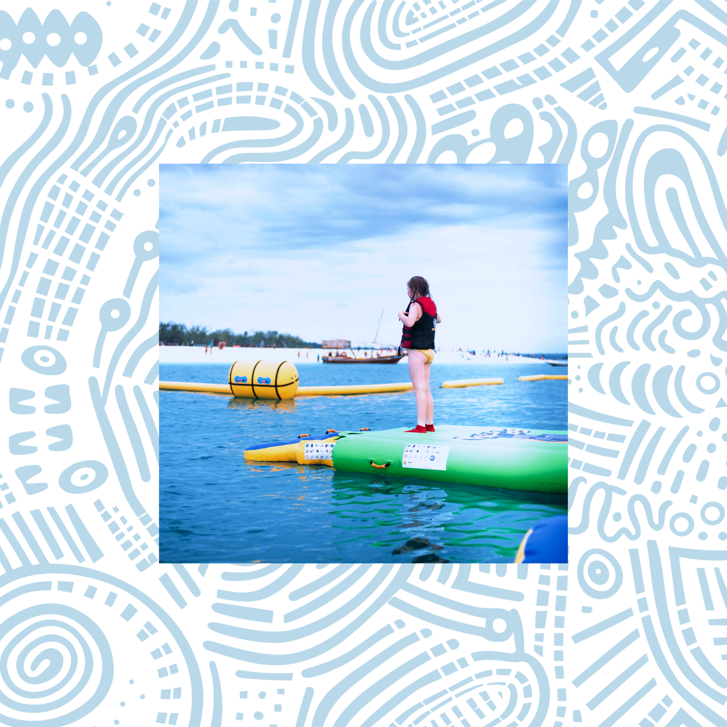 A young girl standing on a green stand-up paddleboard on a body of water, wearing a life jacket and yellow swimsuit, with a cloudy sky overhead and boats in the background.