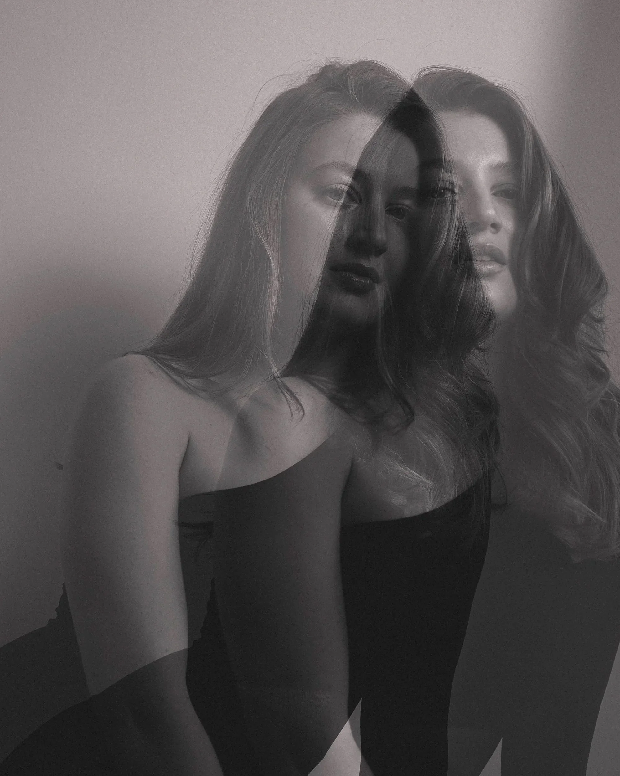 Schwarz-weiß-Fotografie von zwei Frauen, die übereinandergelegt sind, mit wechselndem Fokus auf ihre Gesichter und Oberkörper.