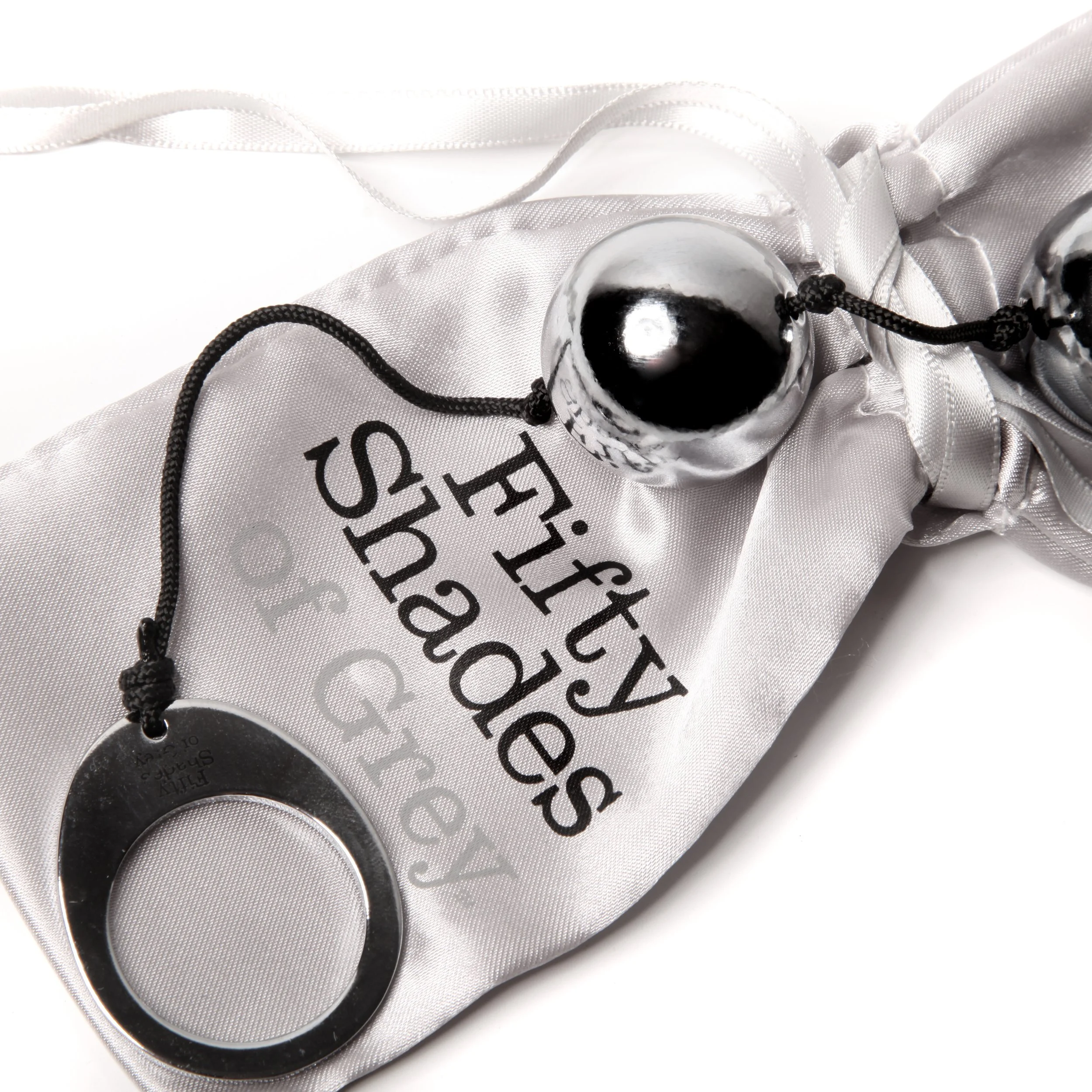 Silver shiny ring attached to a black string with a silver and black sphere, resting on a white satin fabric with black text reading 'Thuy Designs and G.'