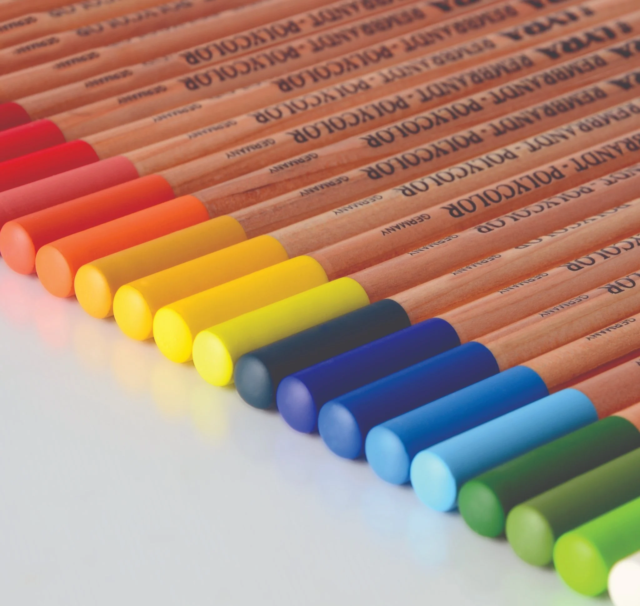 A row of colored pencils arranged in a rainbow gradient from red to green, with wood bodies and color-coated tips.