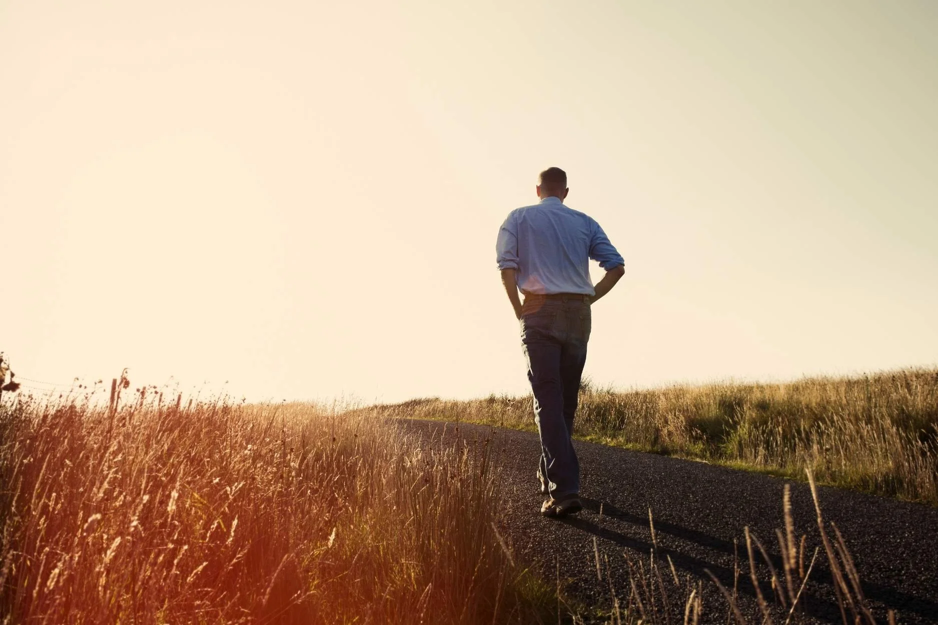 Man walking on a road alone towards the sunset