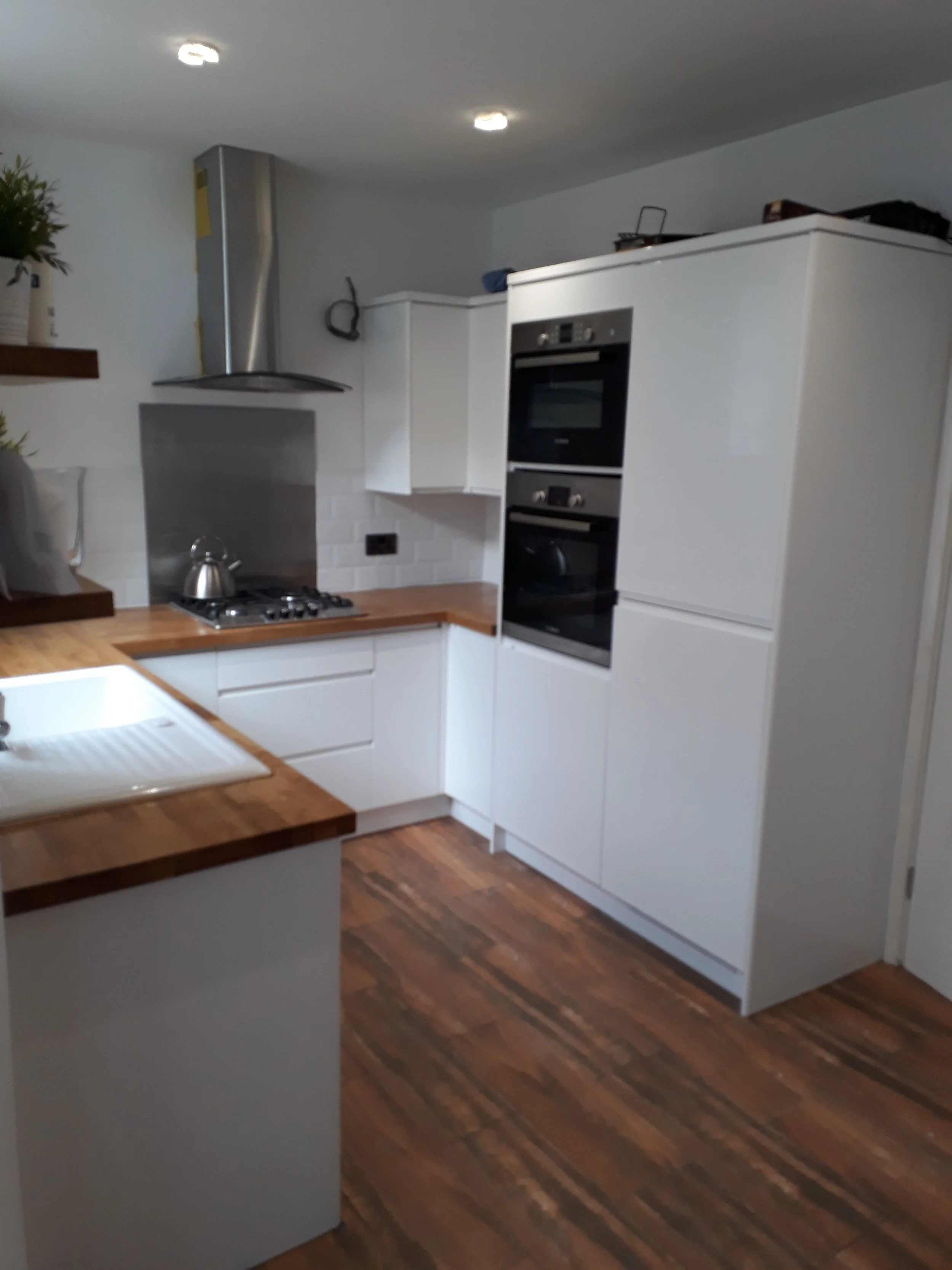 Magasfényű, fehér fogantyú nélküli konyhabútor, tölgy, Osmoval kezelt munkapulttal. Kerámia mosogatóval.  Baal Design