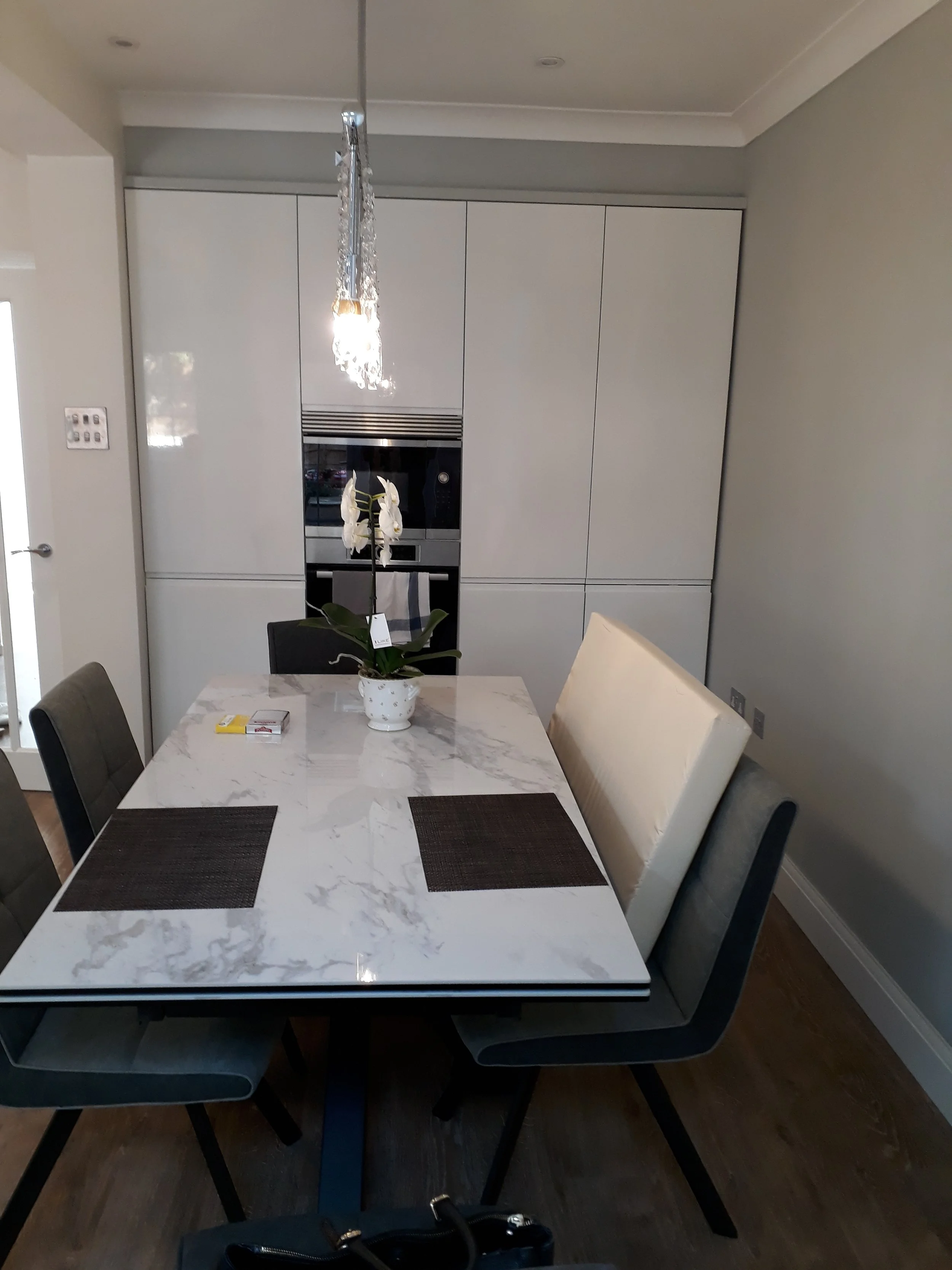 Magasfényű, fehér, fogantyú nélküli front, quartz munkalappal.