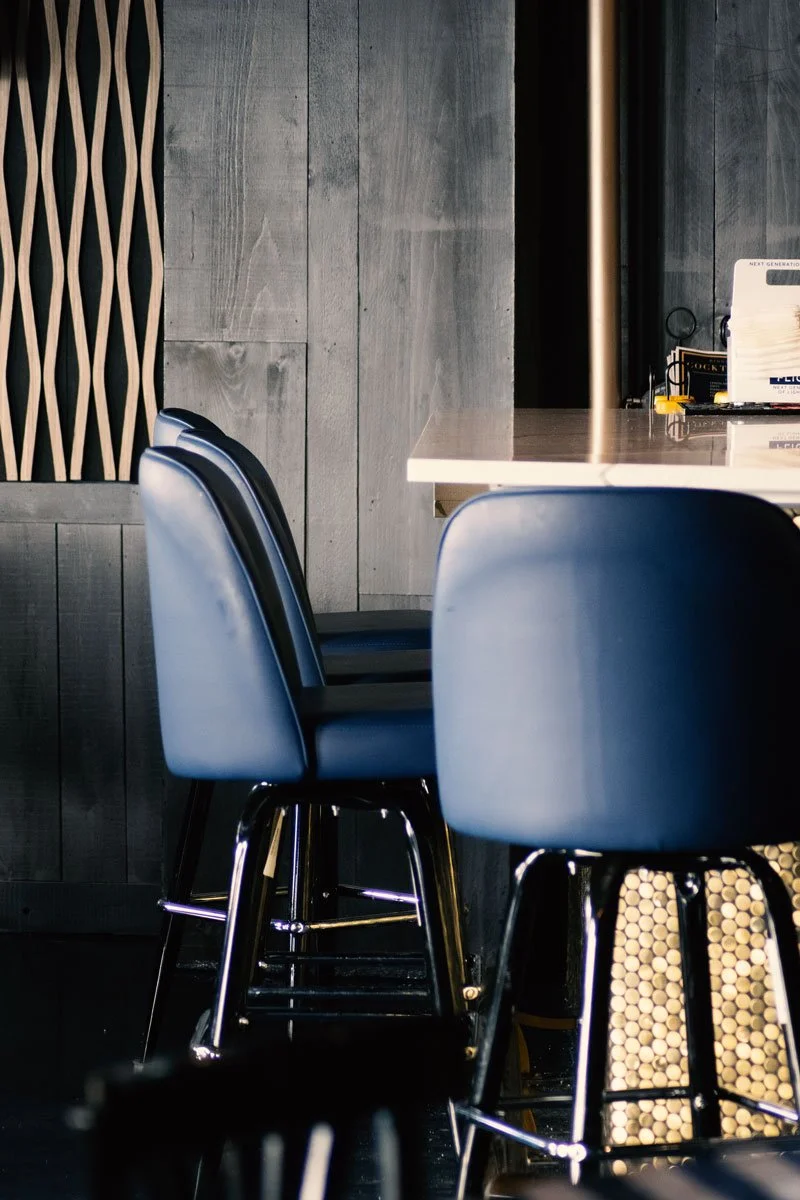 Chic, Empty bar stools at a counter in a modern cafe or restaurant with wooden wall panels.