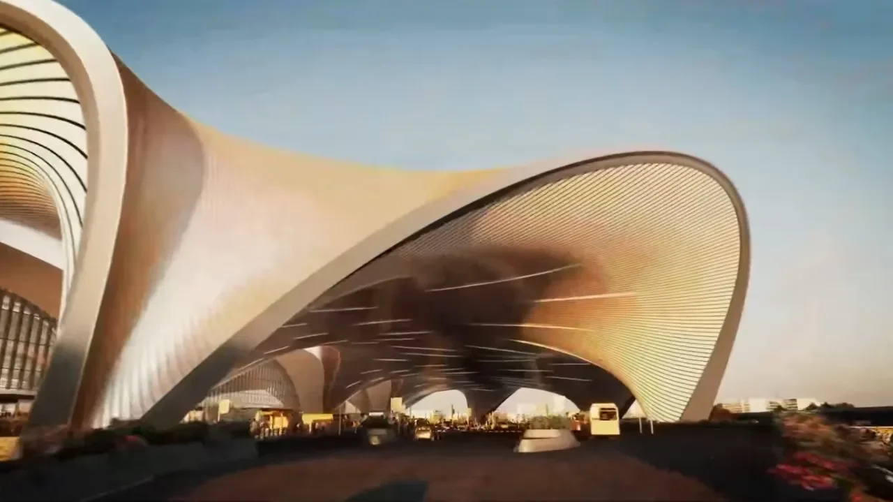 Modern architectural building with curved, layered roof structures and large glass windows, set against a clear blue sky.