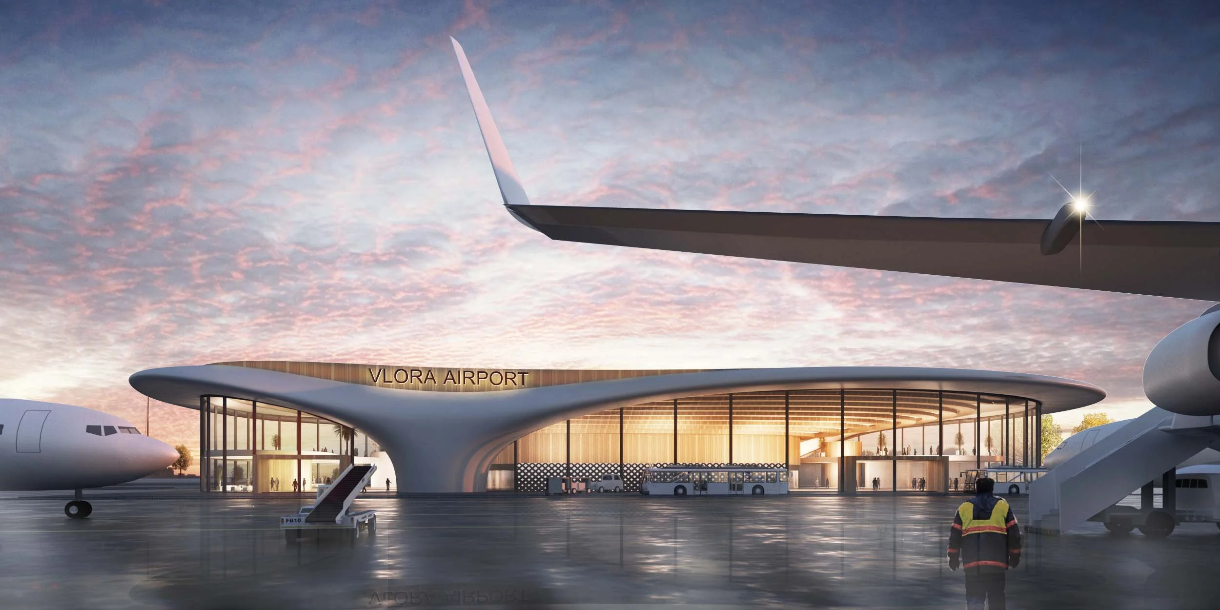 Modern airport terminal with the sign 'VLORA AIRPORT', glass windows illuminated from inside, several airplanes parked outside, and a person in a reflective jacket walking near the stairs, against a pink and blue sky at sunset.