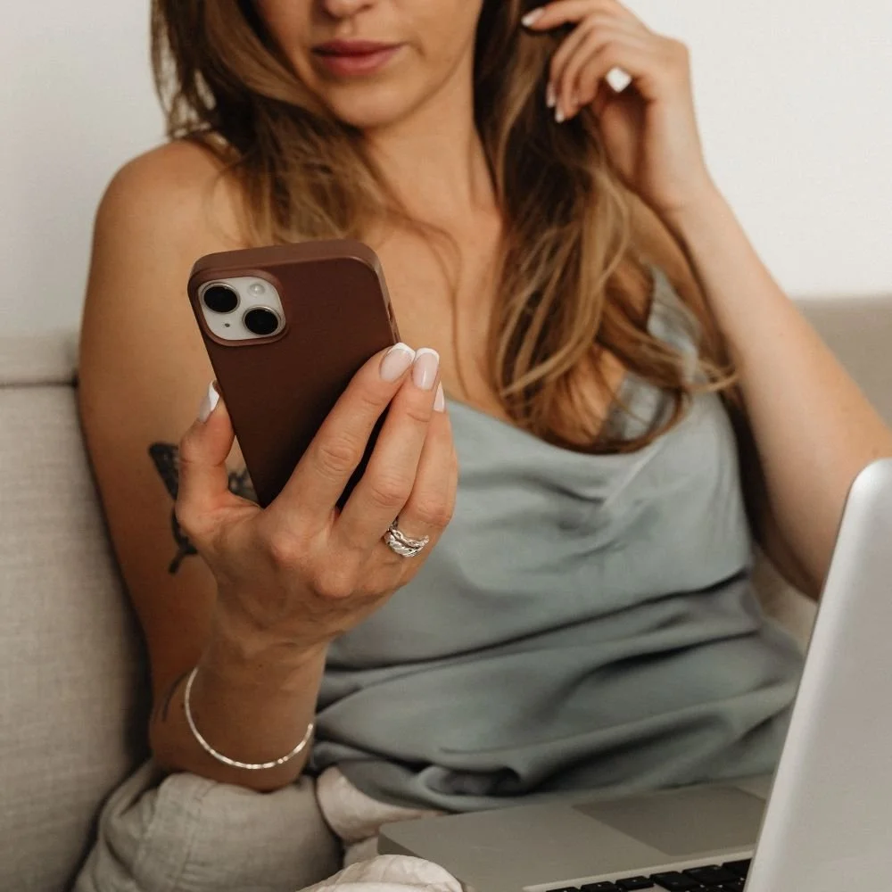 Woman sits holding a phone looking at an email from Preparations Skin Spa