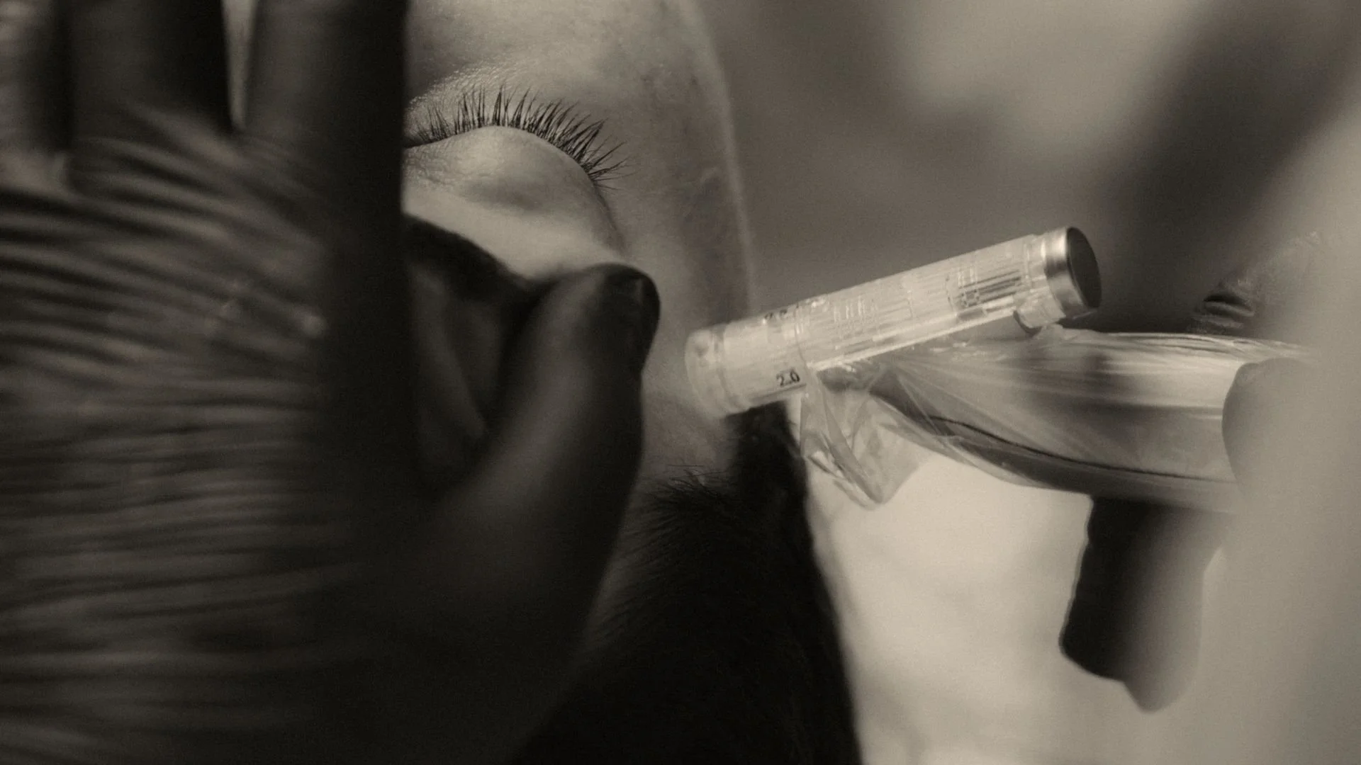A close-up of a medical professional administering an injection into a person's face, with the person’s eye closed and eyelashes visible.