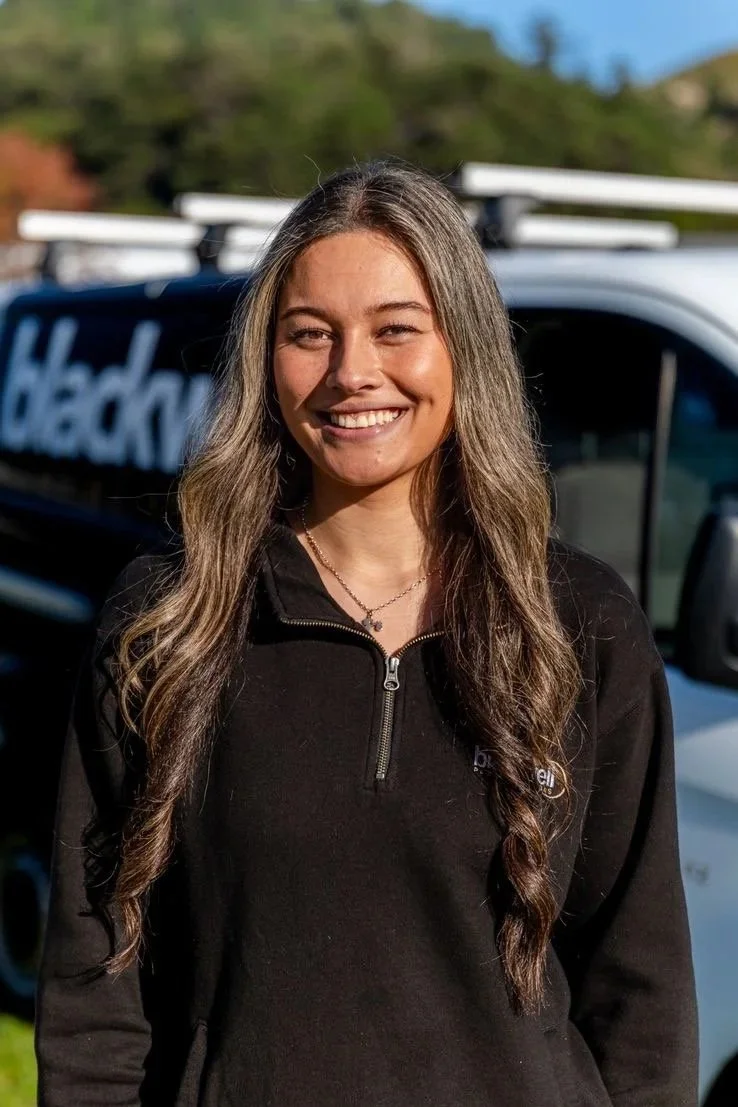 A photo of Victoria Stowers who has long, wavy hair and is smiling outdoors.