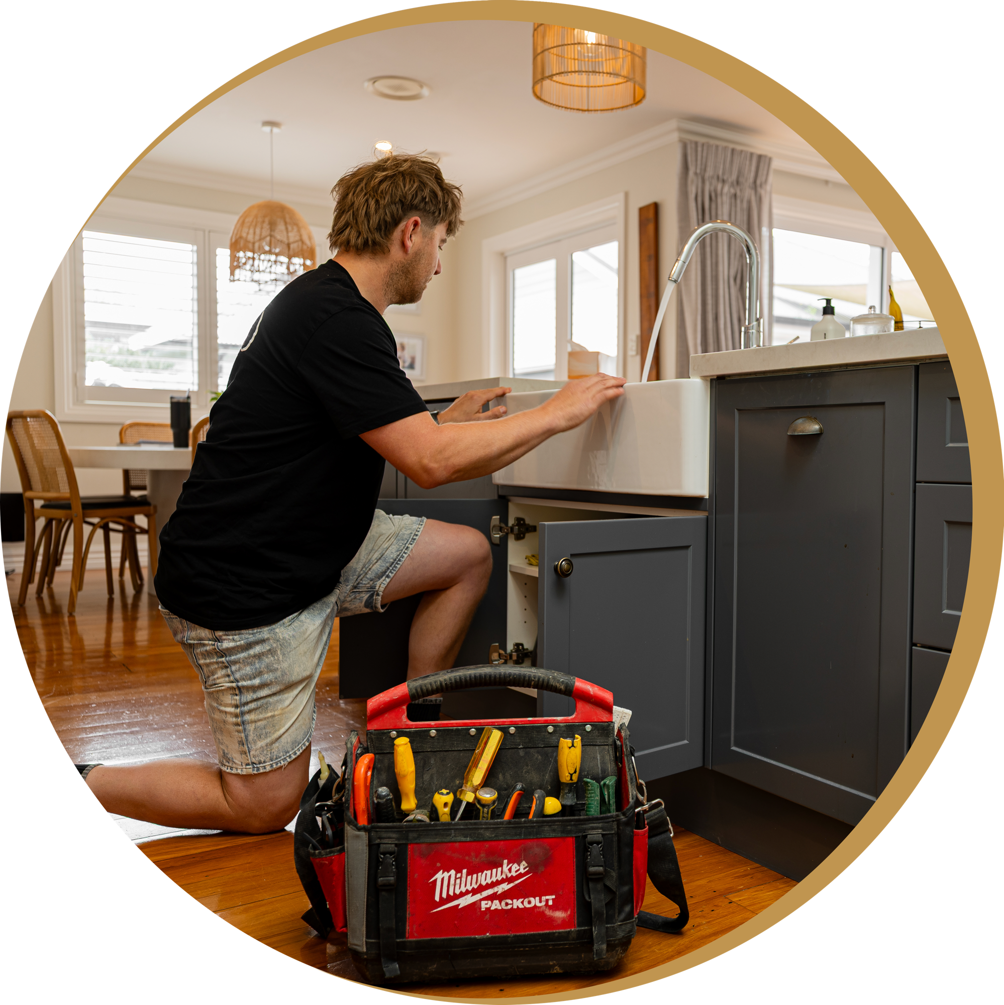 Blackwell Plumbing and Gas employee working in the kitchen with a tool bag on the floor.