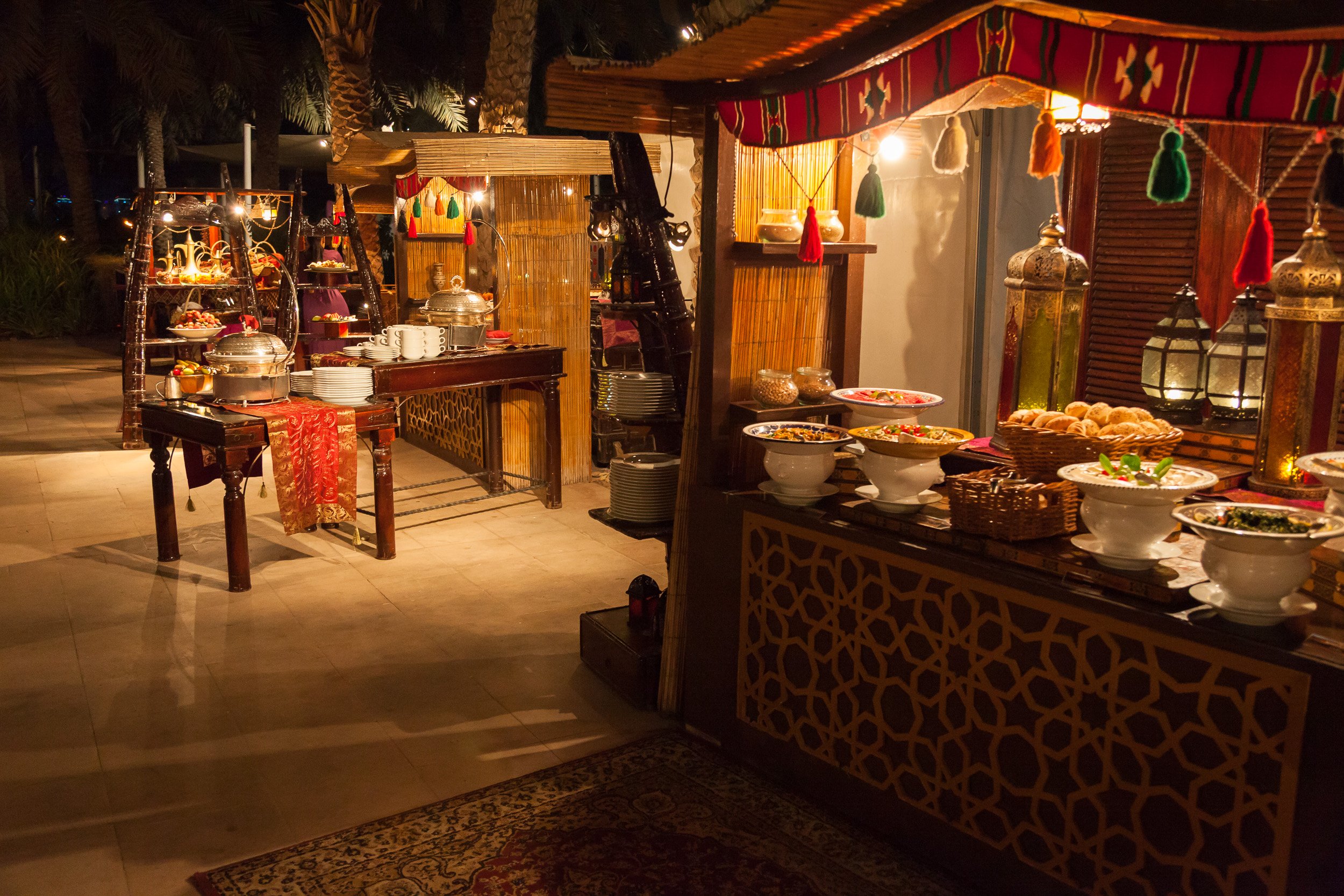 An Arabian-style outdoor buffet in Dubai, lit by lanterns and warm evening light.