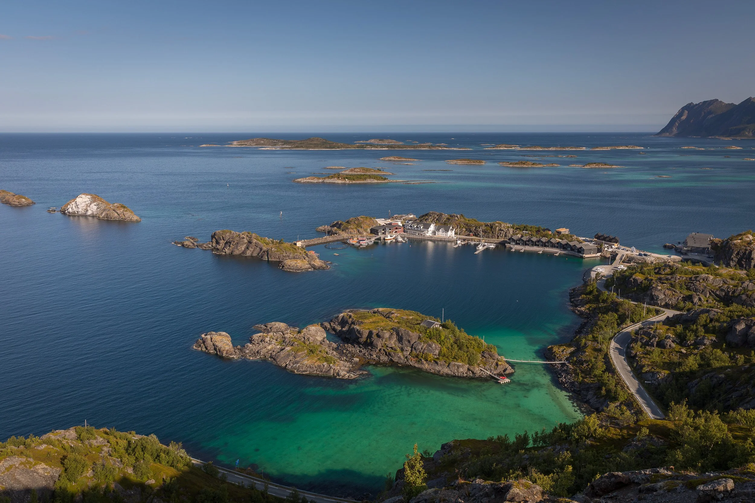 Hamn seen from above, surrounded by small islands, deep blue water and vivid turquoise shallows along Senja’s outer coast.