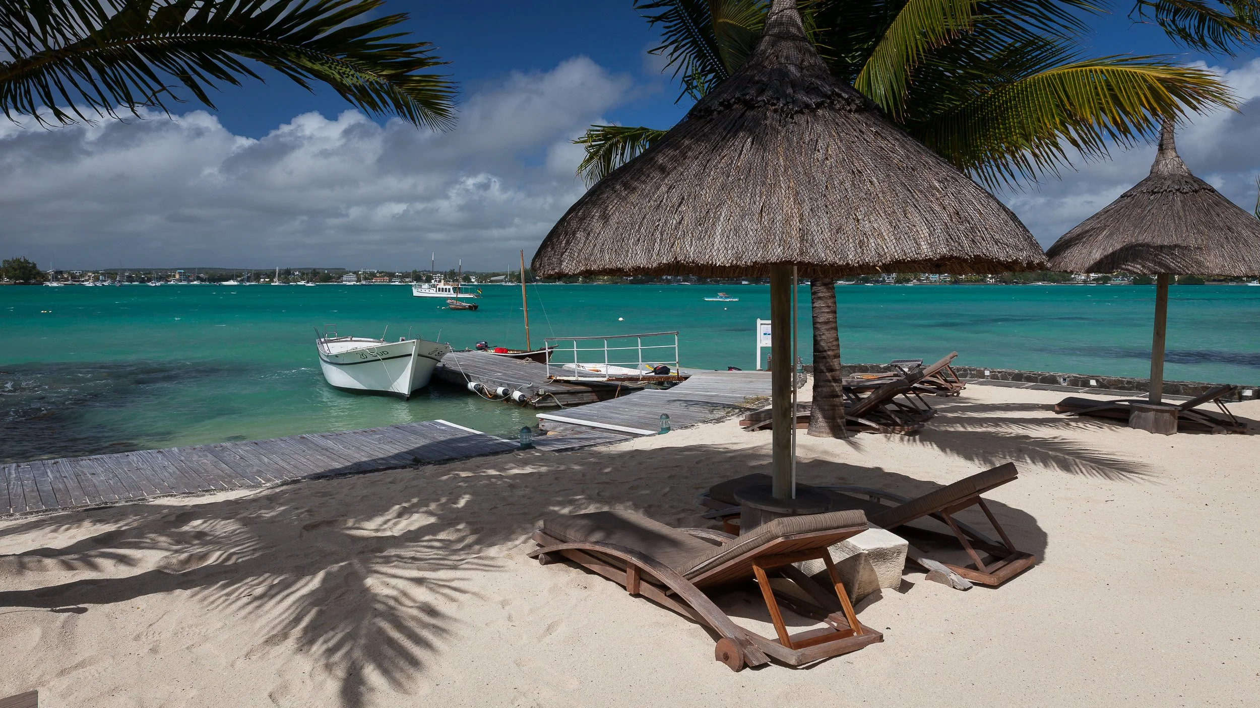 Relaxed lounge at 20° Sud in Grand Baie, Mauritius, opening onto a reflecting pool and palm-fringed bay on the island’s north coast.