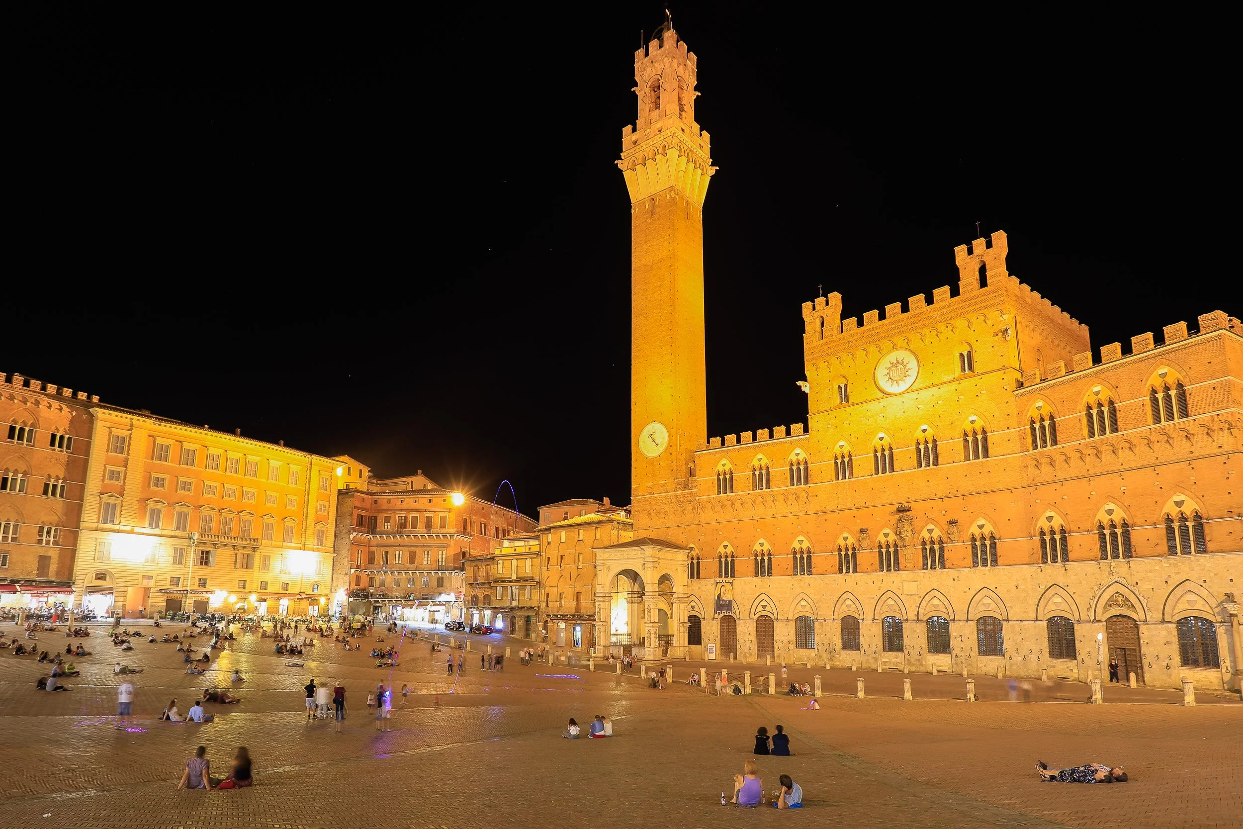 Piazza del Campo in Siena on a summer night, with Palazzo Pubblico and Torre del Mangia dominating the square.