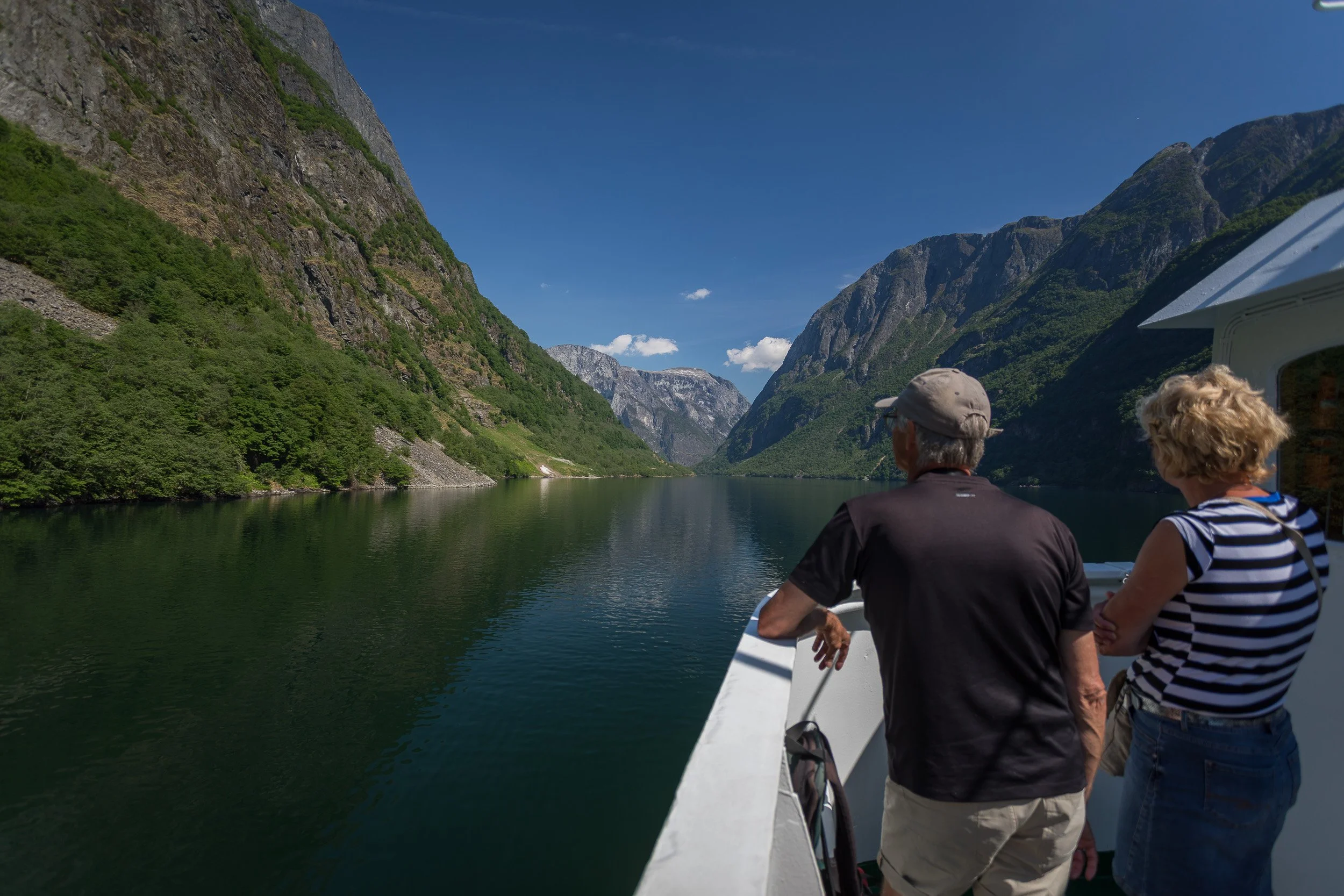On the bow, heading out of Nærøyfjorden, with steep green walls and glassy water framing the route like a natural cathedral.